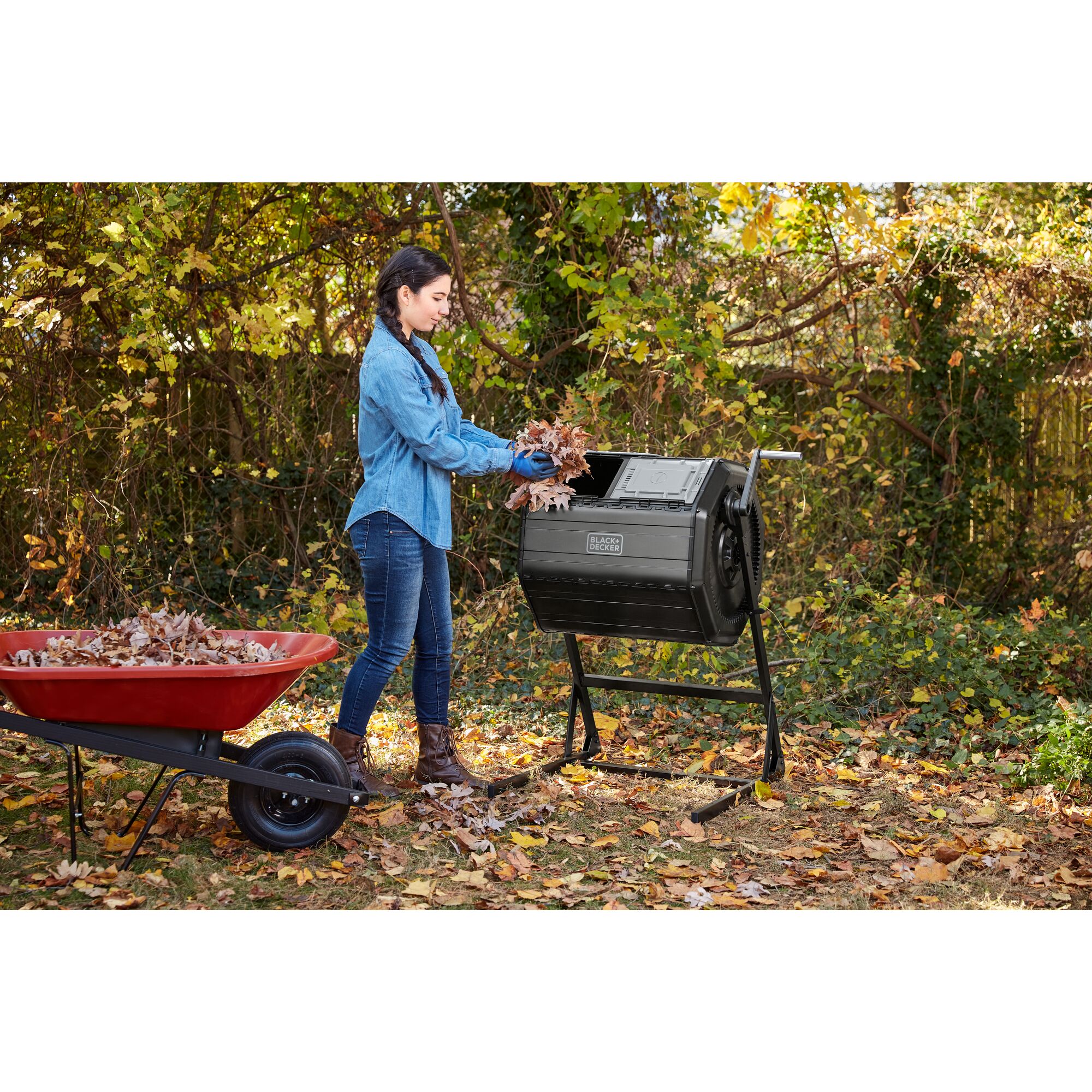 Woman putting leaves in the left chamber of the BLACK+DECKER 40 Gallon Dual Chamber Tumbler Composter