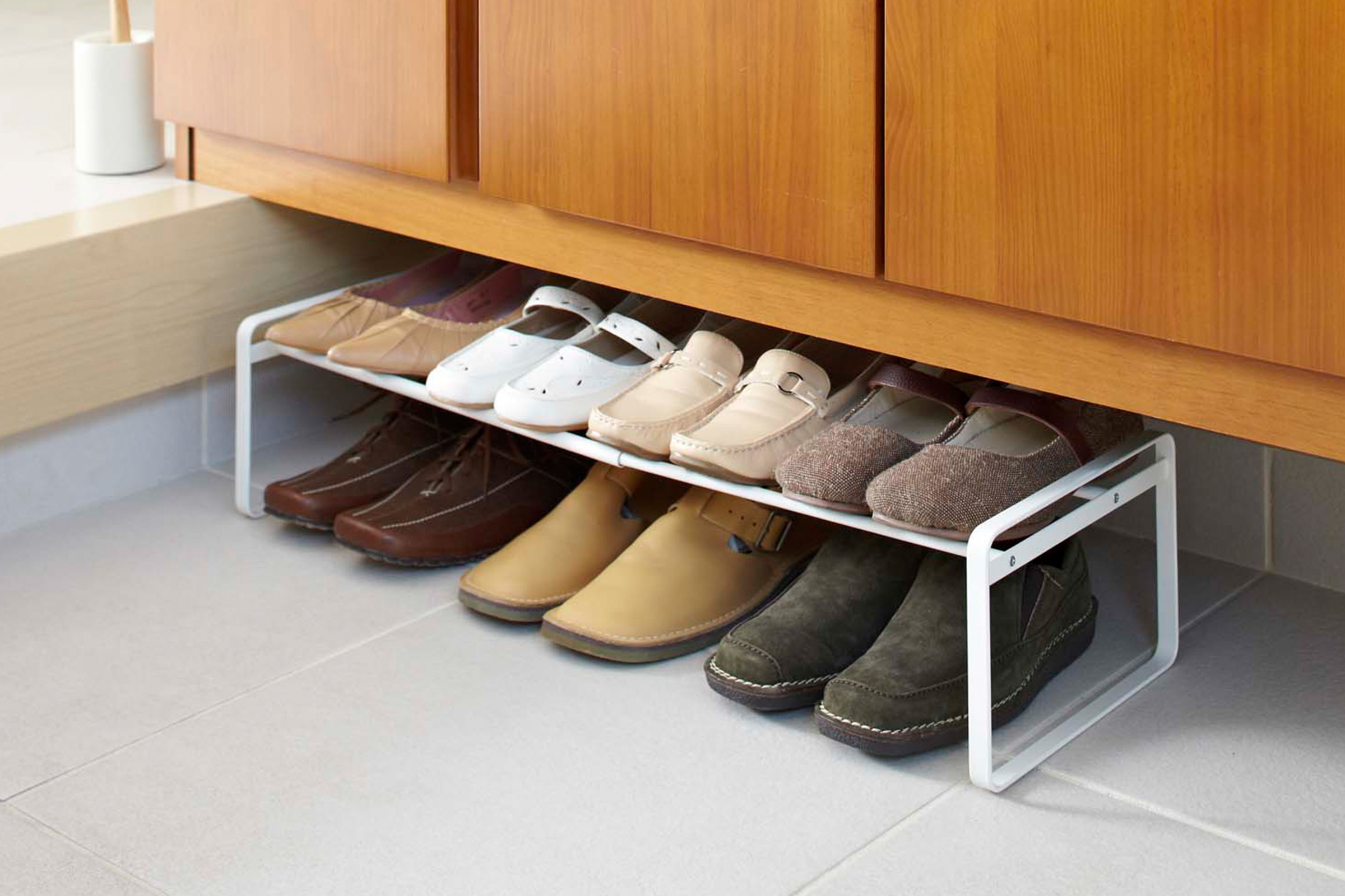 Stackable Shoe Rack by Yamazaki Home in white in an entryway holding seven pairs of shoes.