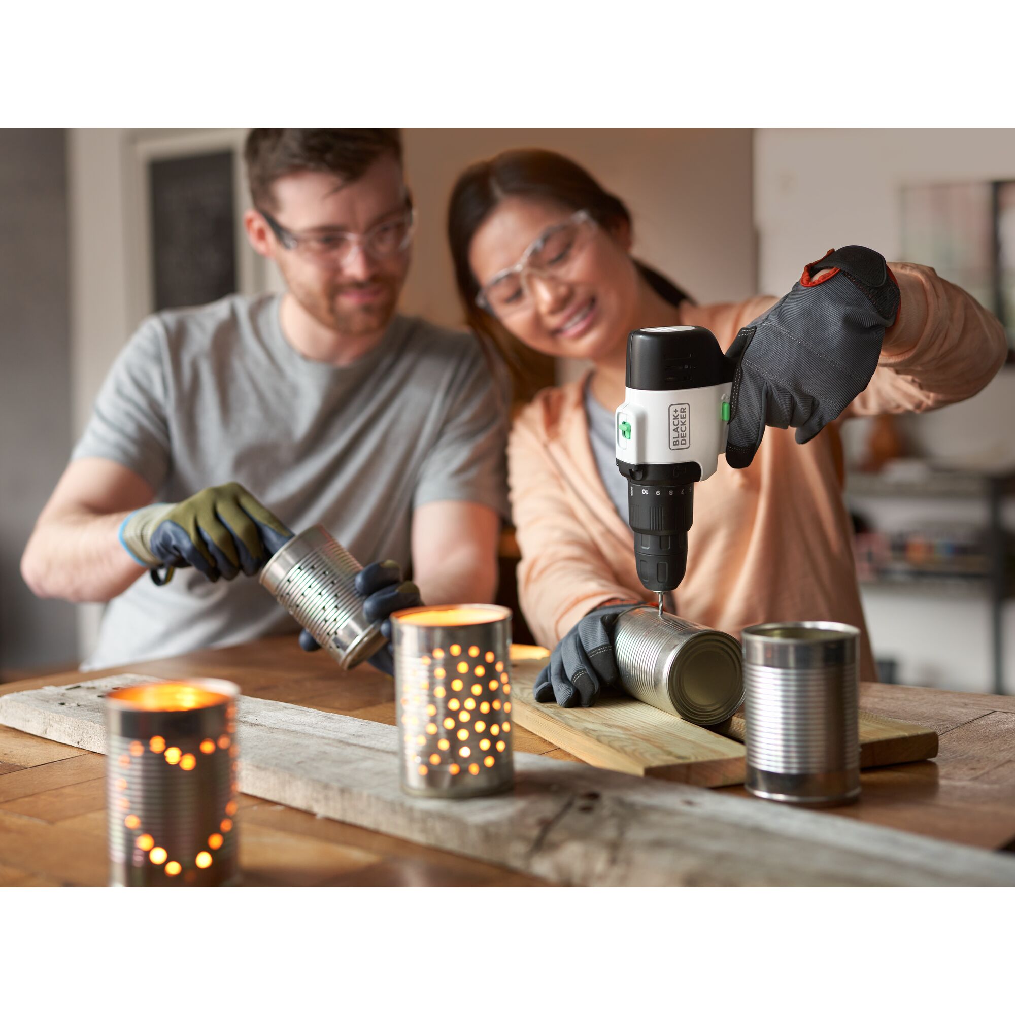 Woman using reviva™ 12V MAX* Hammer Drill/Driver to drill holes in soup cans for a craft project with her husband.