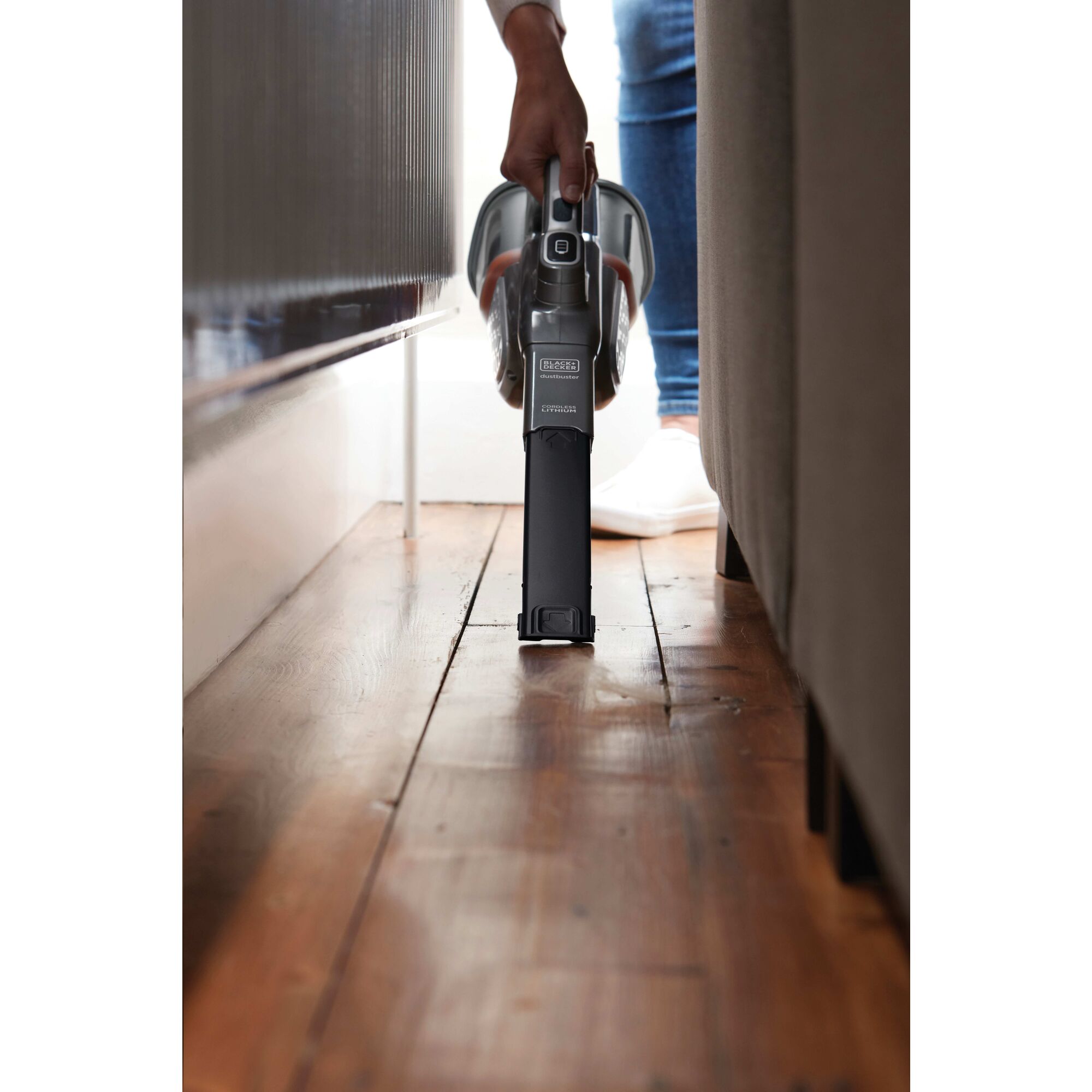 16 Volt MAX dustbuster Advanced Clean plus Hand Vacuum being used to clean narrow places behind sofa.