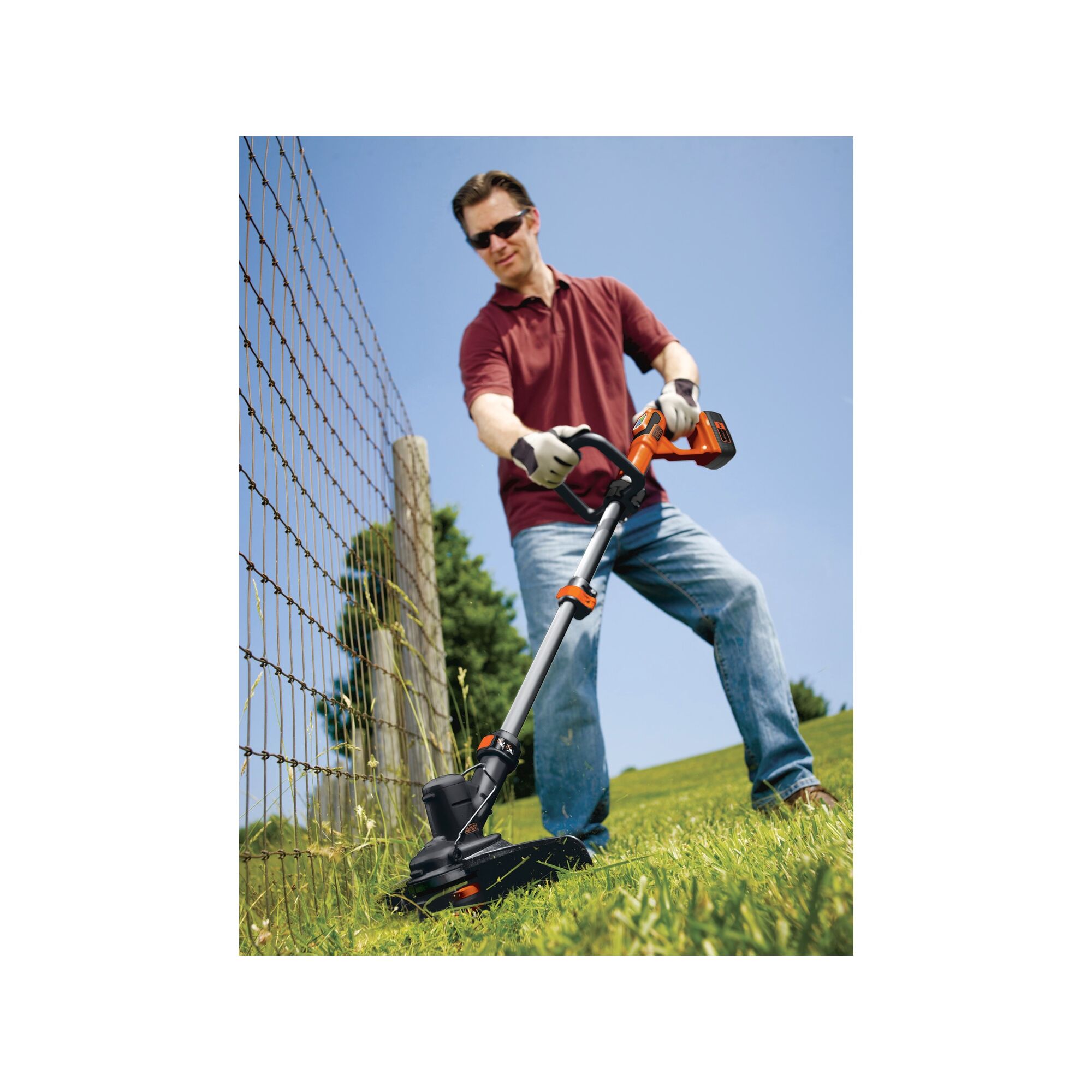 Man using string trimmer near a wire fence