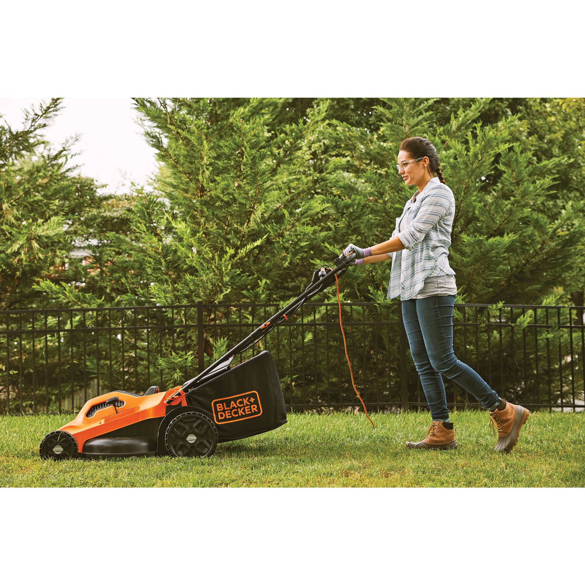 Person pushing the Black and decker 13 amp 20 degree corded electric lawn mower to cut grass in a yard
