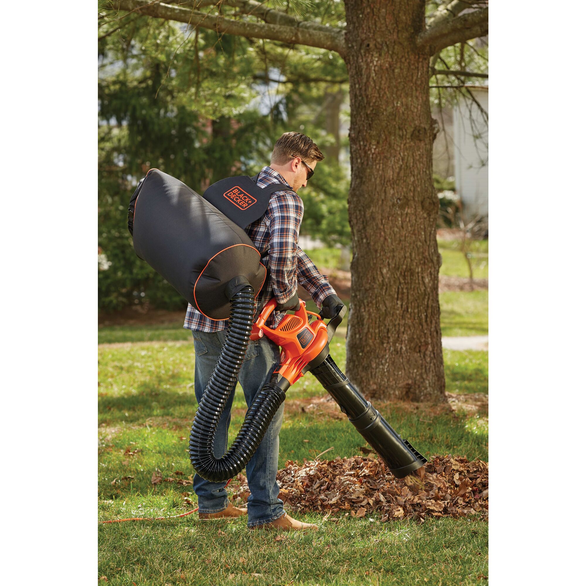 3 in 1 VACPACK 12 Ampere Leaf Blower Vacuum and Mulcher being used by person to clear leaves from ground outdoors.