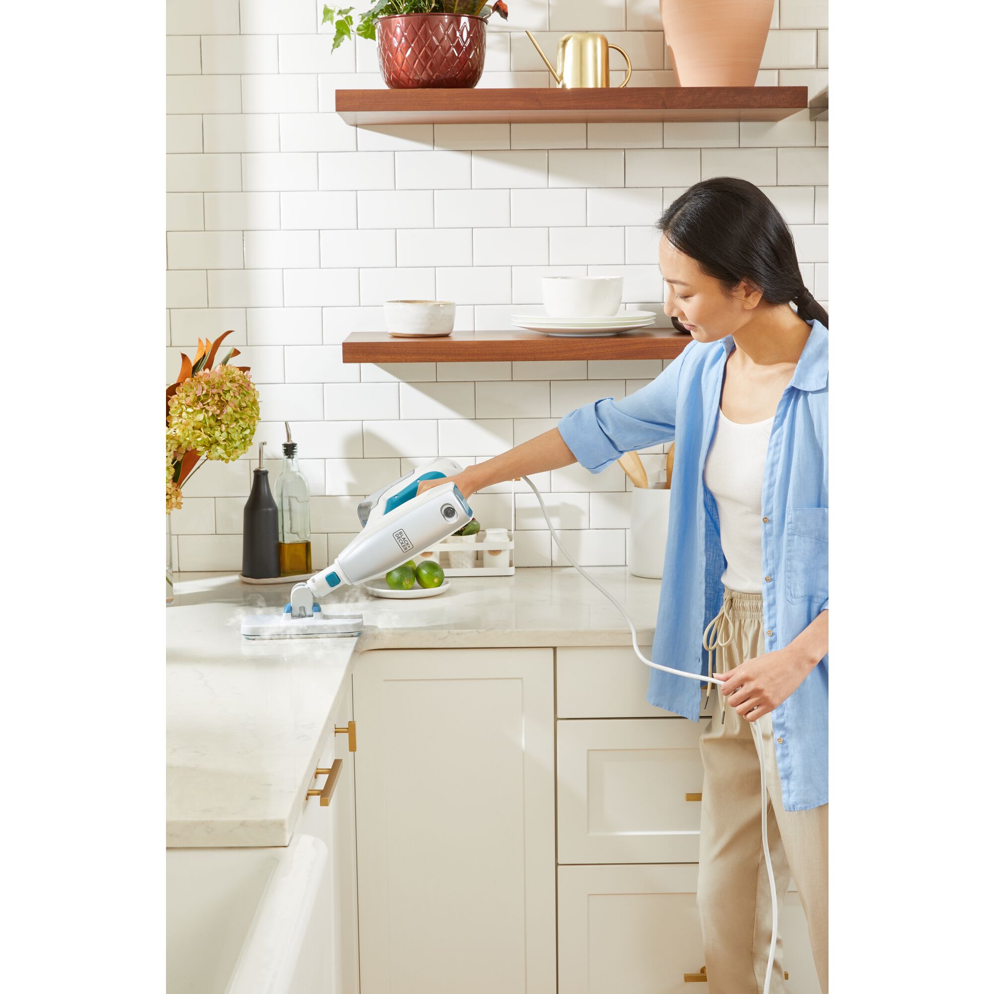 Woman cleaning kitchen counter with steam mop accessory