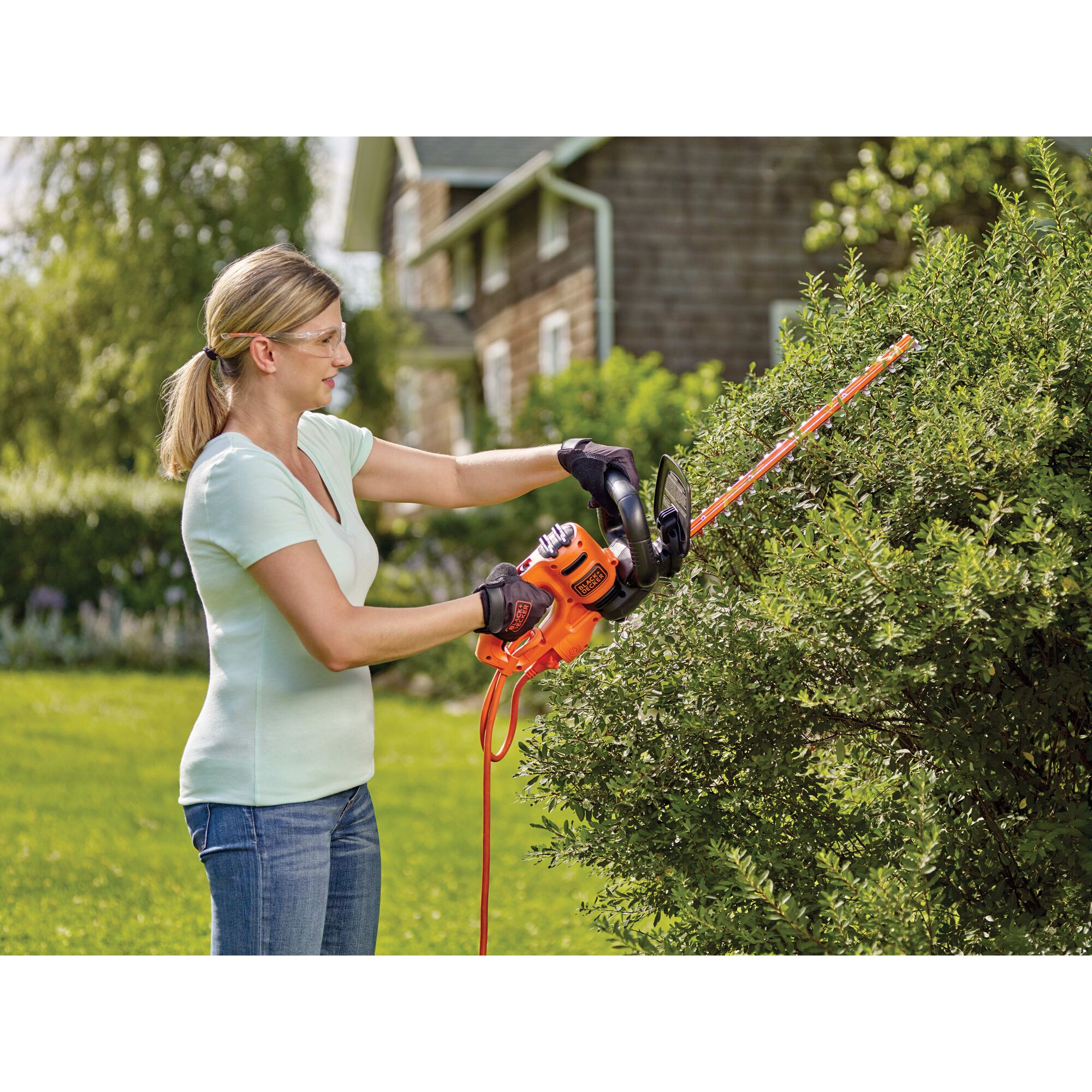 18 inch Electric hedge trimmer being used by a person to trim bushes.