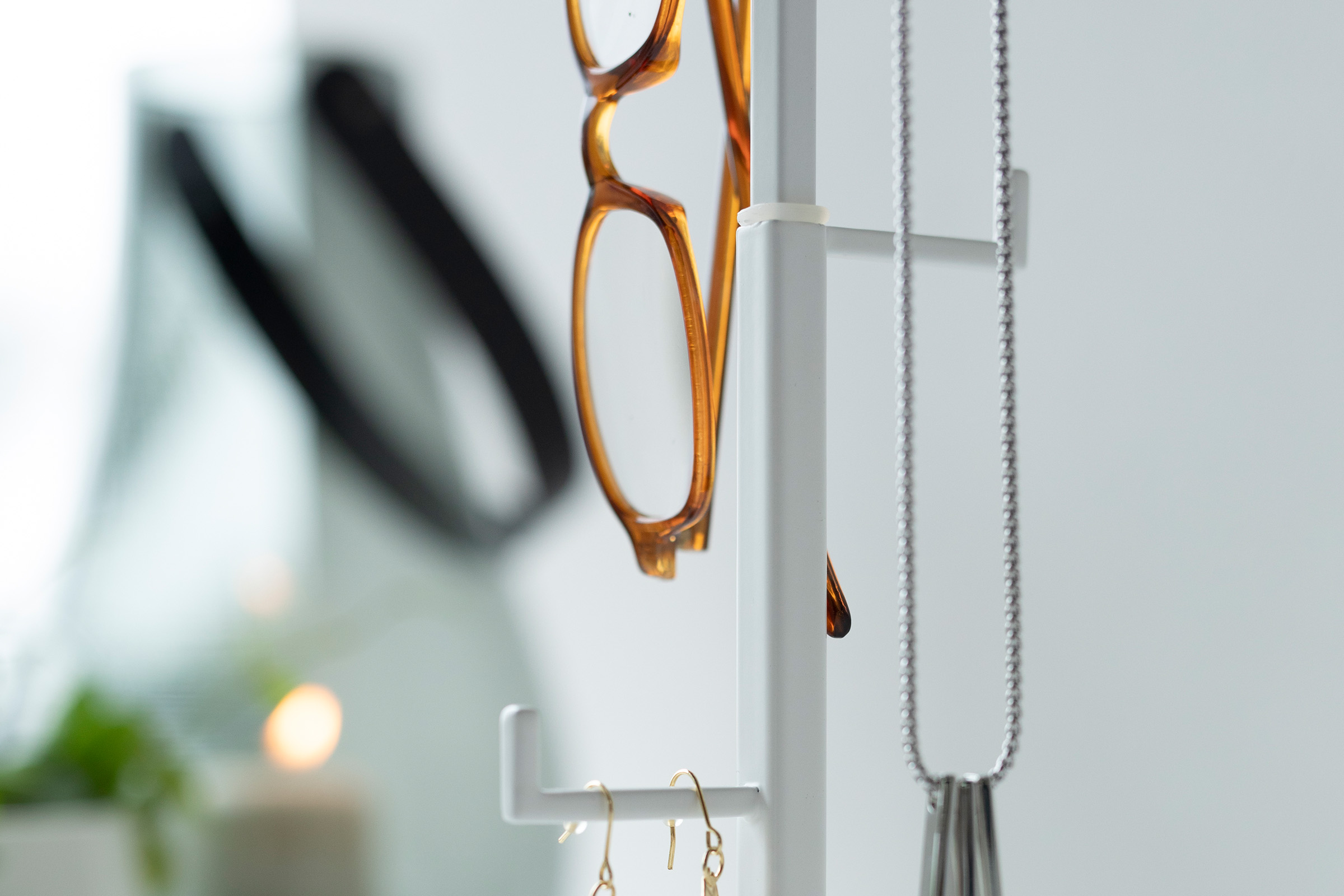 Close-up view of one of the rungs on the Tree Accessory Stand by Yamazaki Home in white holding several accessories.