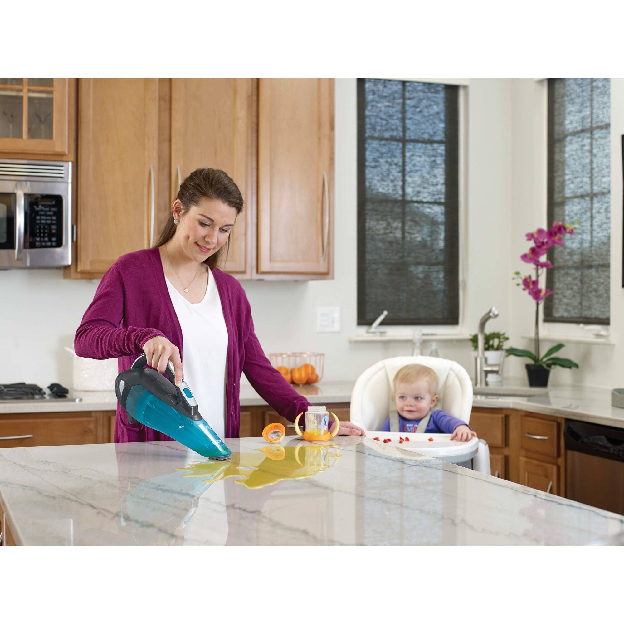 Dustbuster Advanced Clean Wet or Dry Cordless Hand Vacuum being used by person to clean spilled baby juice from kitchen countertop.