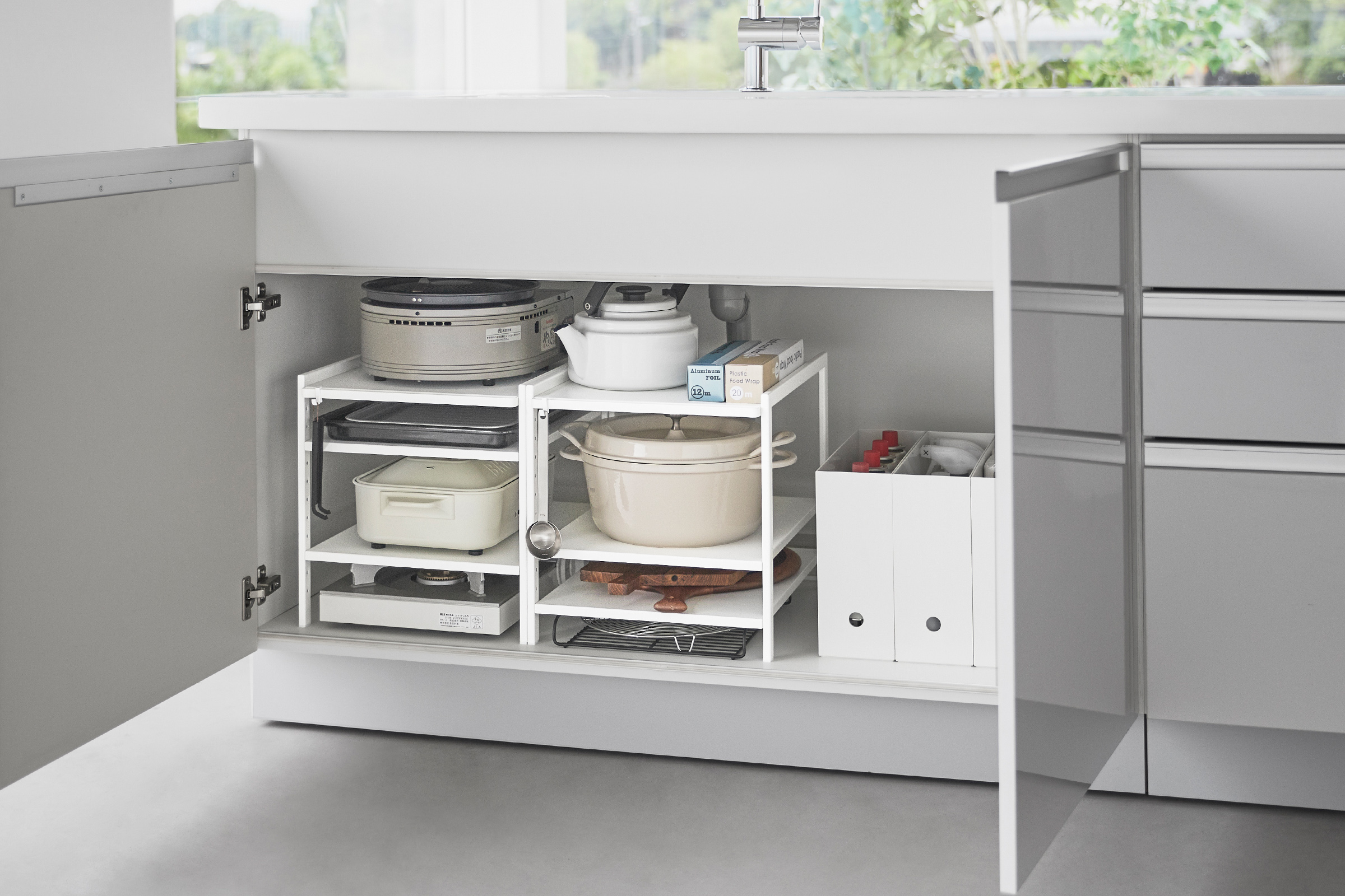 Two of Yamazaki Home Three-Tier Cabinet Storage Rack holding pot and pans and kitchen essentials.