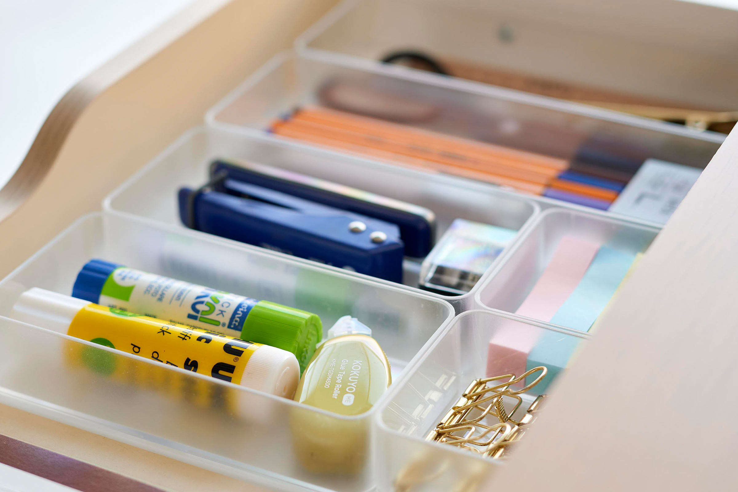 Further close-up image of three different sizes of stackable clear organizers—small, medium, and large—neatly placed in a desk drawer. Made from transparent material, they accommodate stationery items like pens, paper clips, and sticky notes, showcasing their clarity and stackability