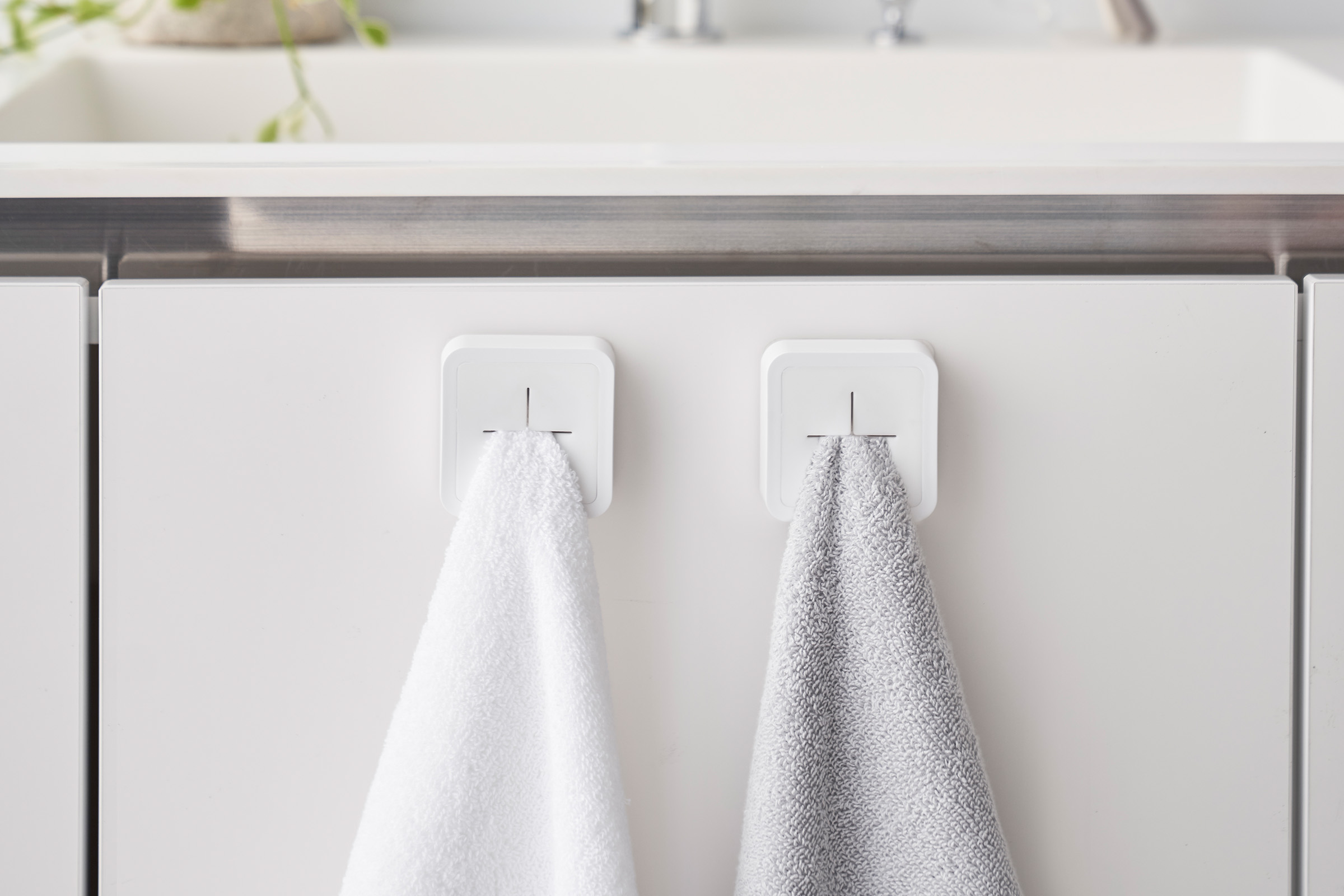 Close up of two white Yamazaki Home Traceless Adhesive Towel Holder with towels inserted