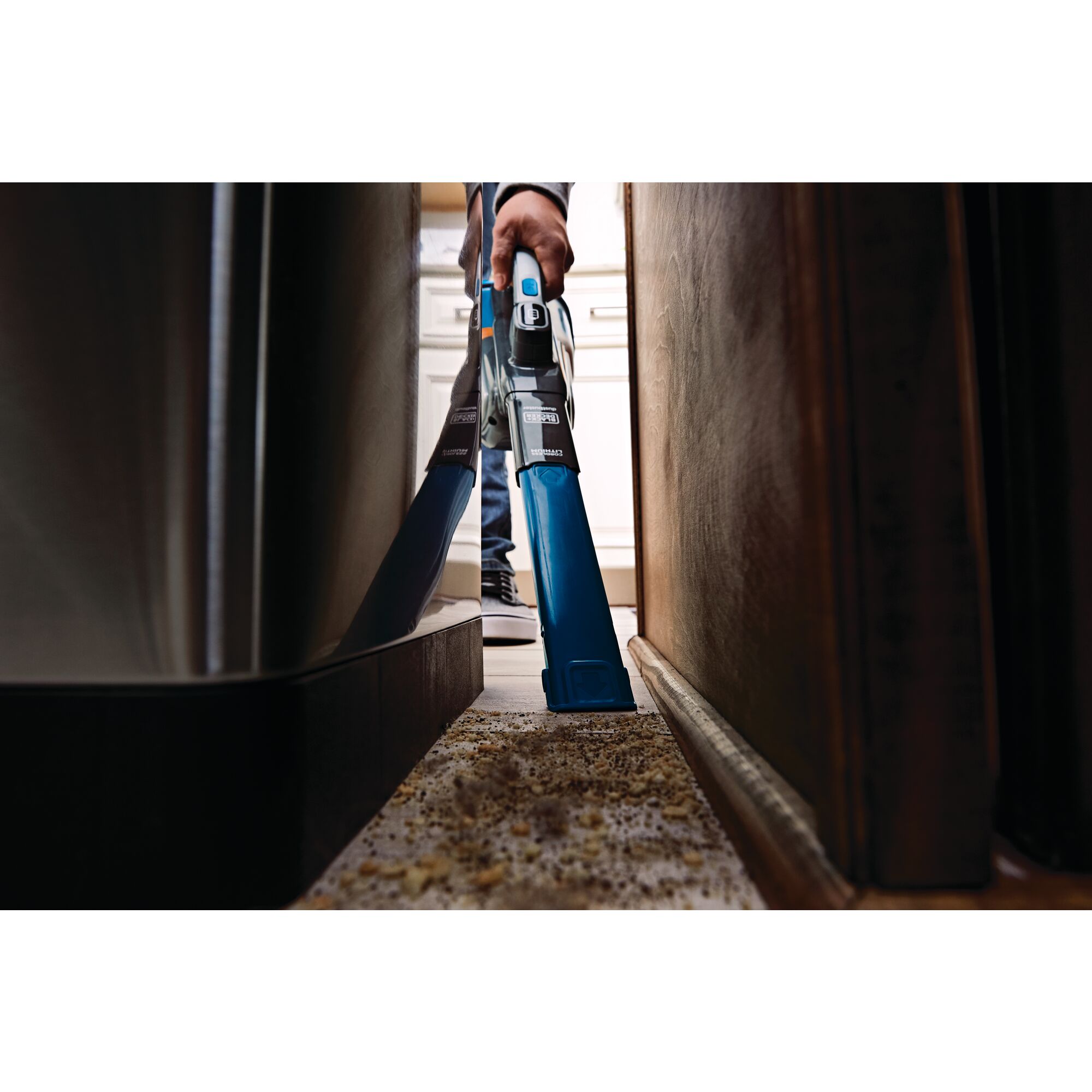 12 volt max dustbuster advanced clean plus cordless hand vacuum being used to vacuum spilled material from a hard to reach gap behind a couch.