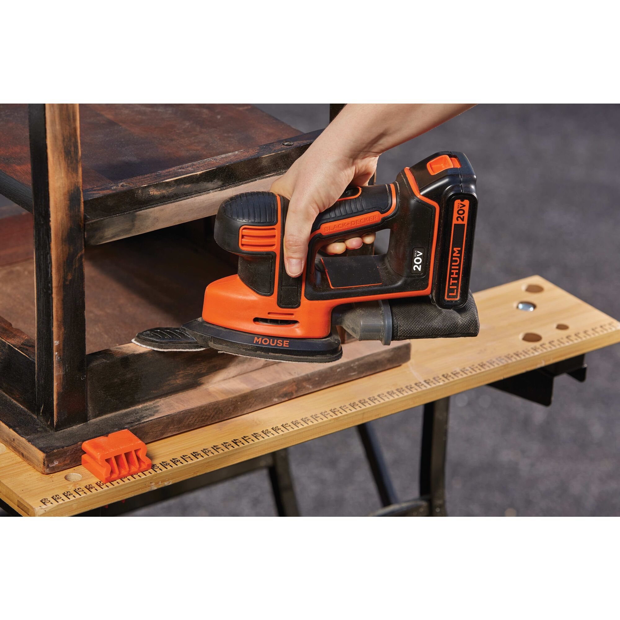 Close up of MOUSE Cordless Sander being used by person to sand wooden stool.
