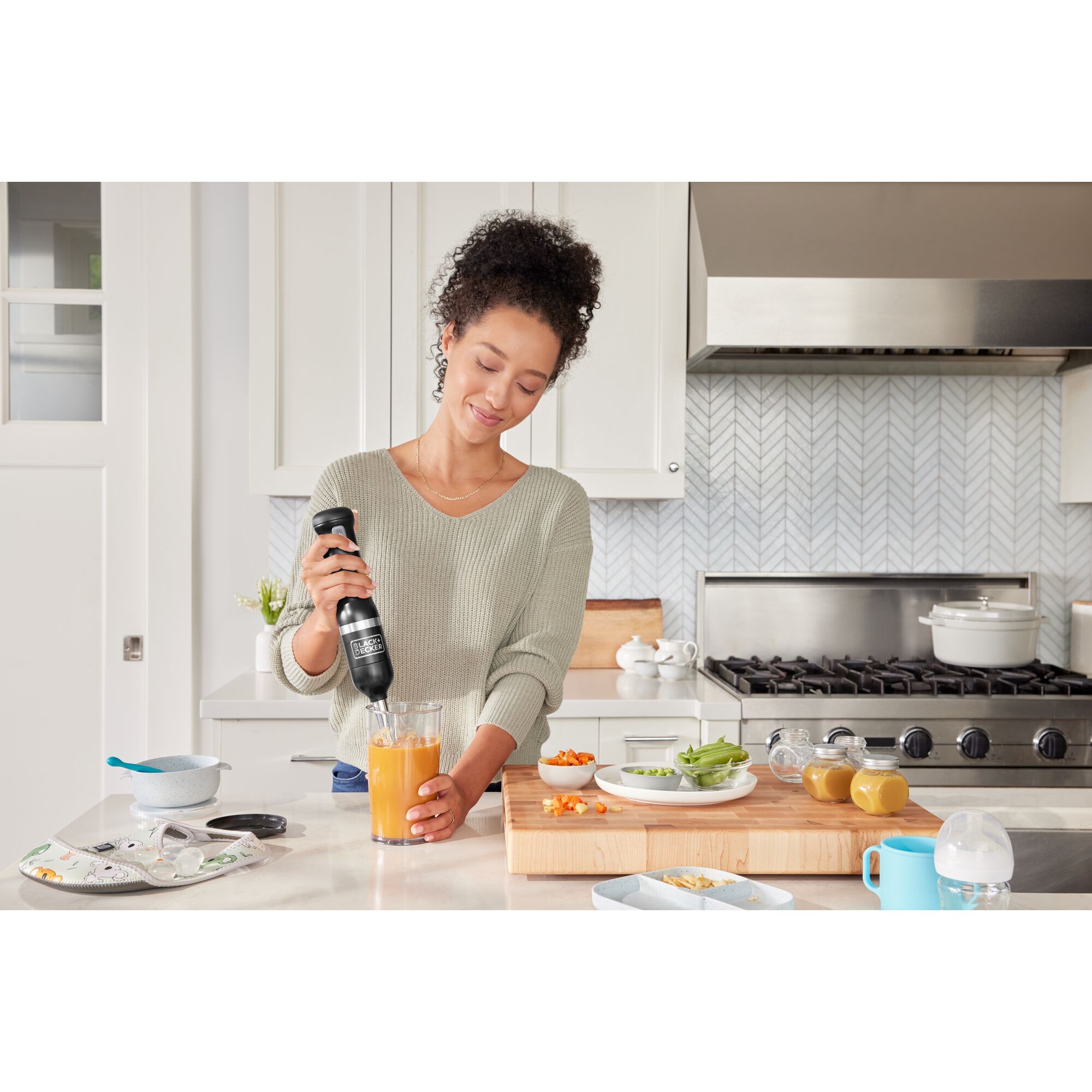 Talent using the black, BLACK+DECKER kitchen wand immersion blender to prepare baby food