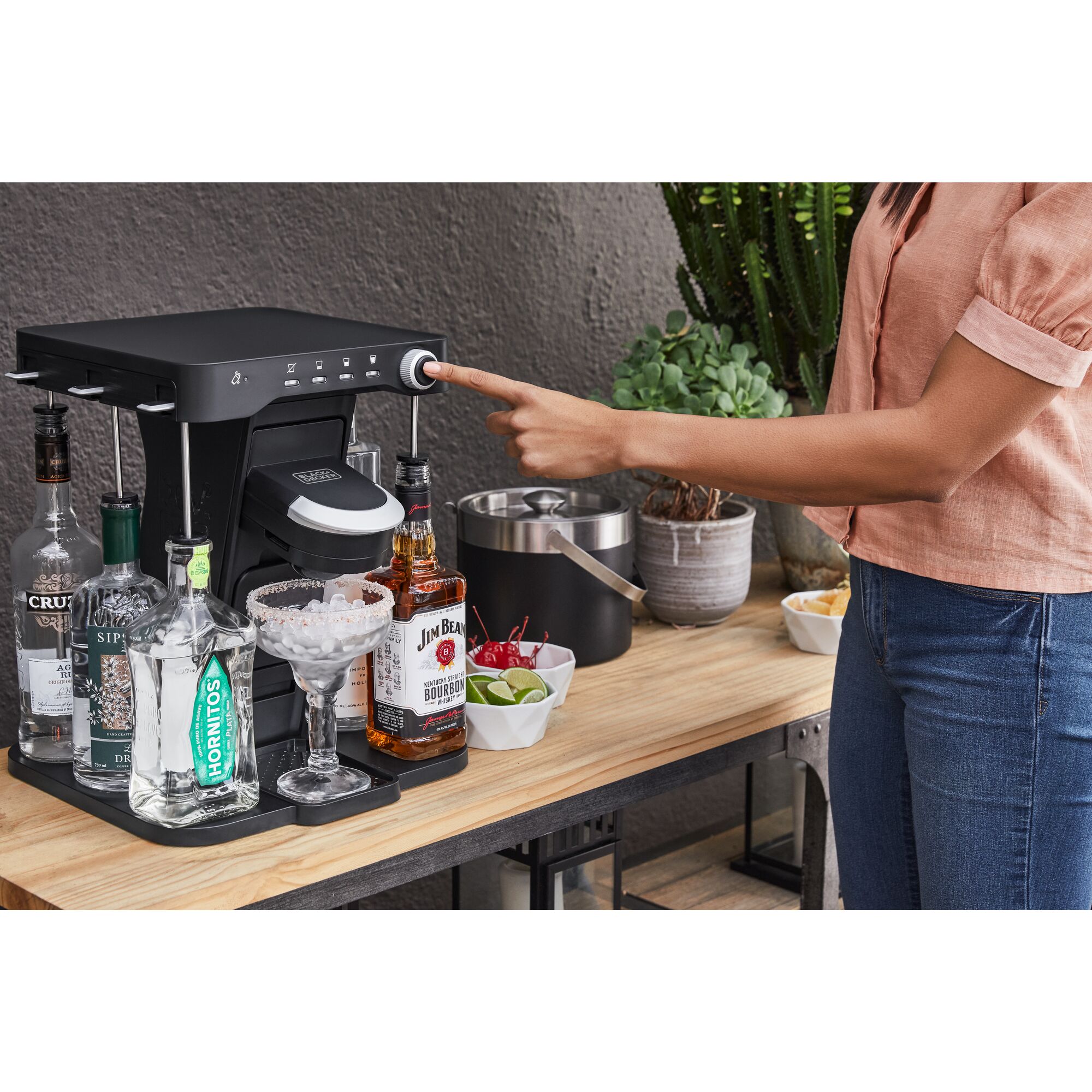 woman, on the patio, pressing the mix button on the bev by BLACK+DECKER\u2122 cocktail maker to make a margarita