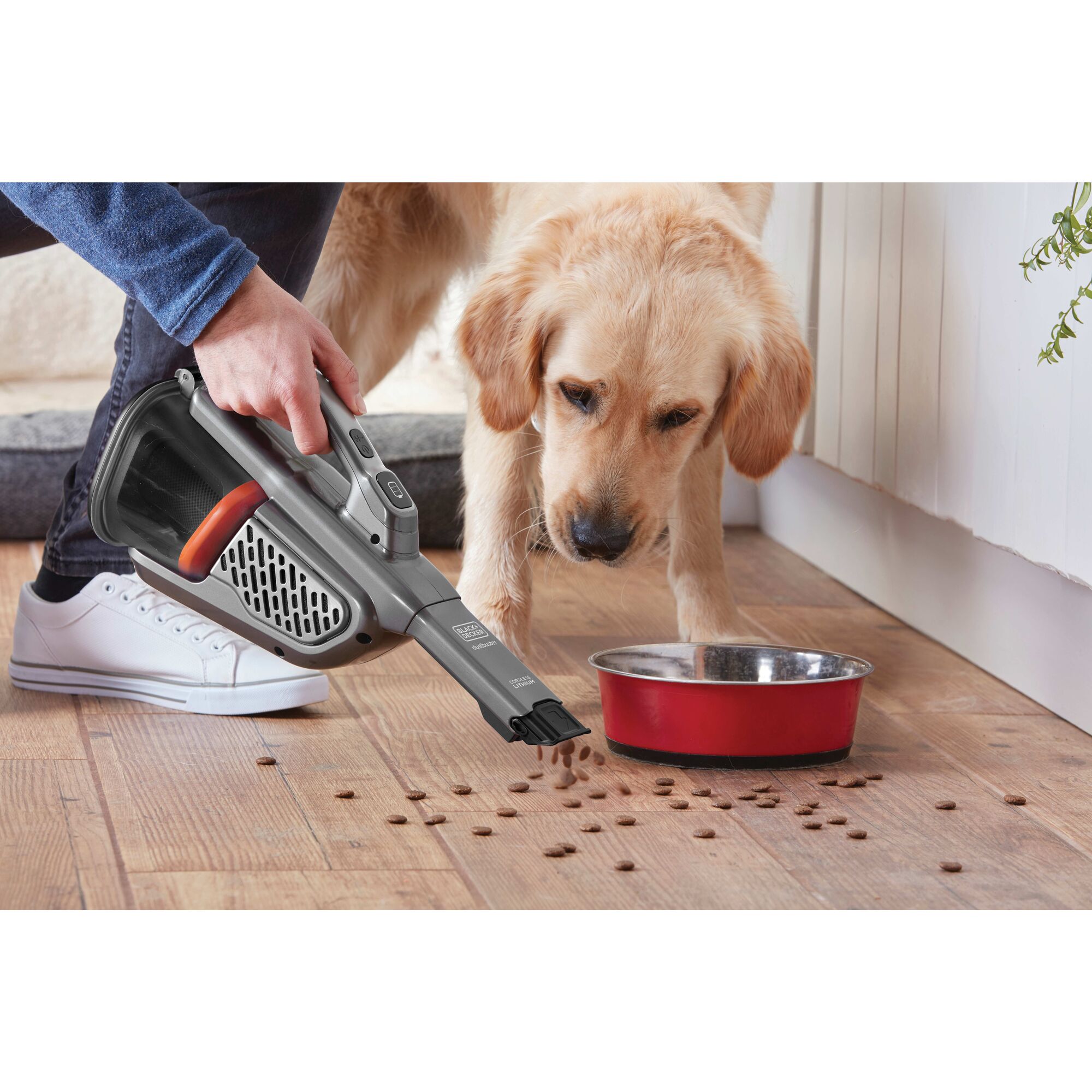 12 volt MAX dustbuster AdvancedClean cordless hand vacuum being used by a person to clean dog food spillage.