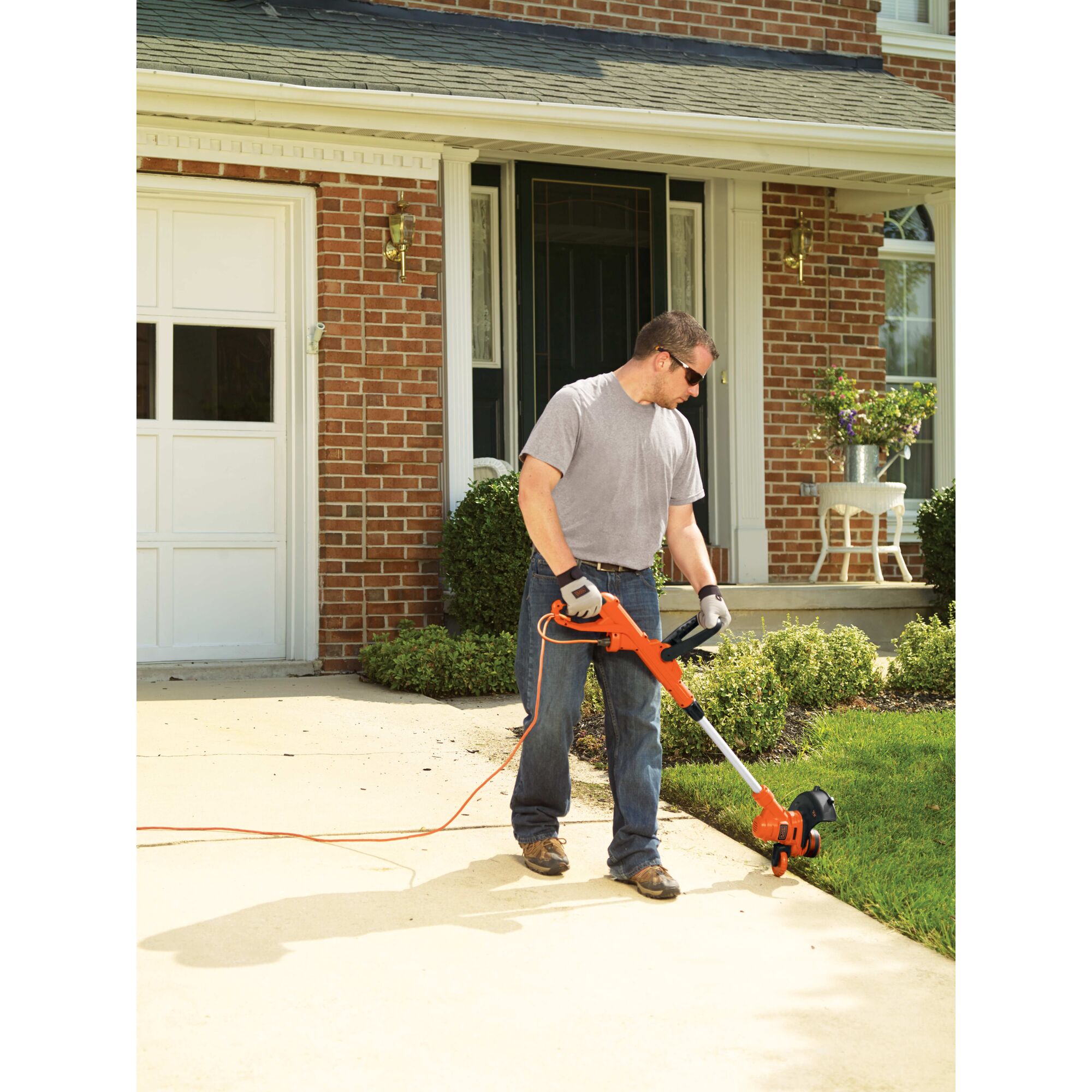 6.5 Ampere 14 inch trimmer edger being used by a person to trim grass.