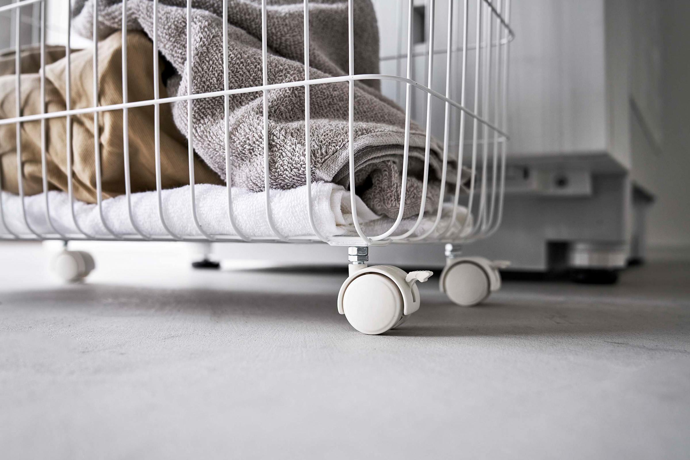 Close-up image of the bottom part of the Rolling Wire Basket by Yamazaki Home in white, showing the white caster wheels.