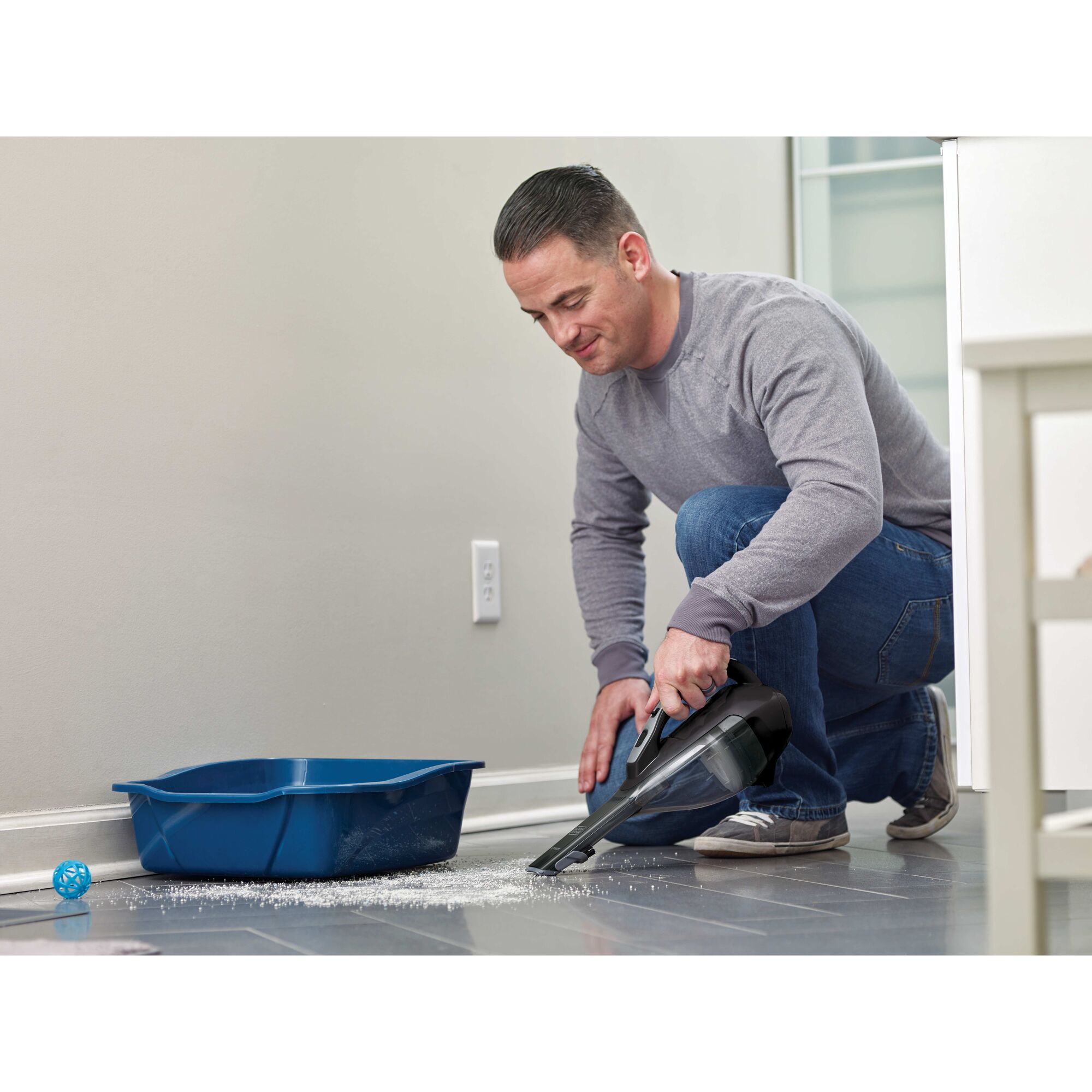 Man using dustbuster handheld vacuum to clean dirt around a blue pail