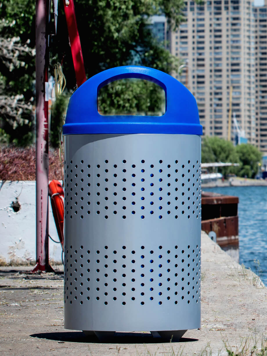 silver metal outdoor recycling container with large capacity liner and blue domed canopy lid to keep contents dry sitting along the waterfront