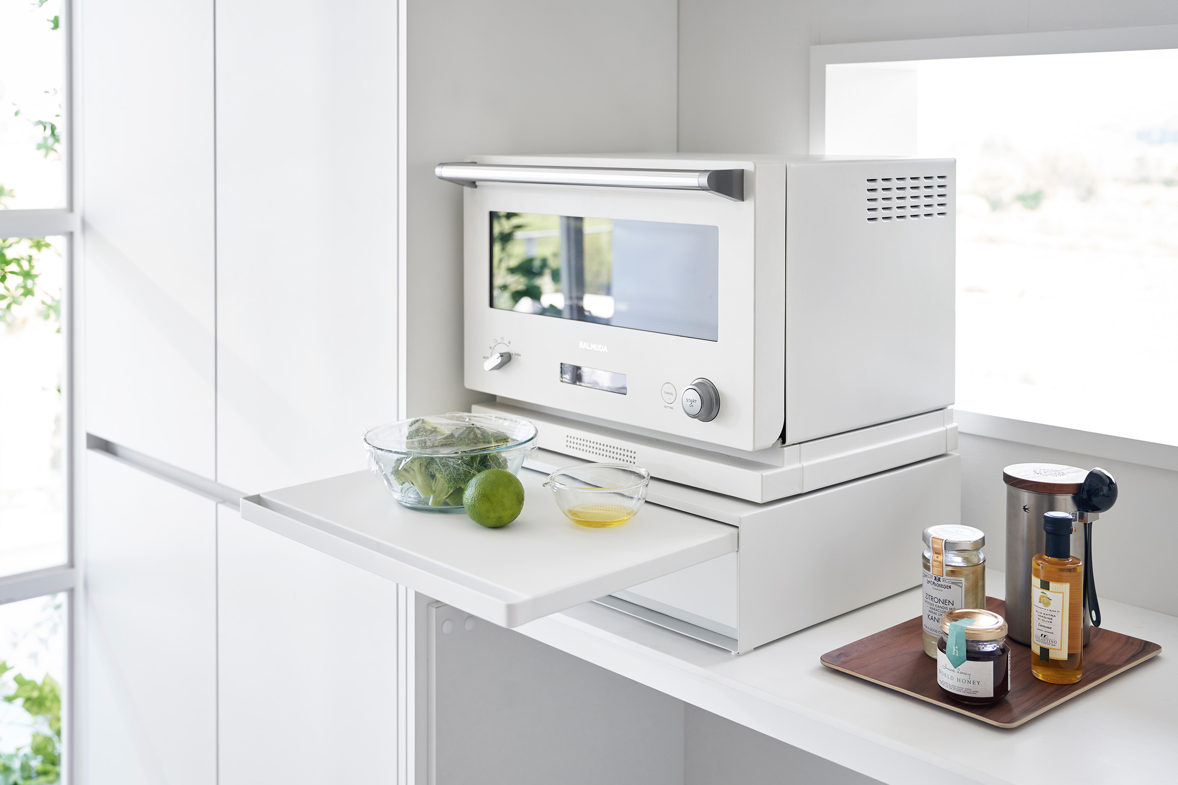 The Countertop Drawer with Pull-Out Shelf by Yamazaki Home in white with the shelf pulled out. Containers of food and a lime sits on the shelf.