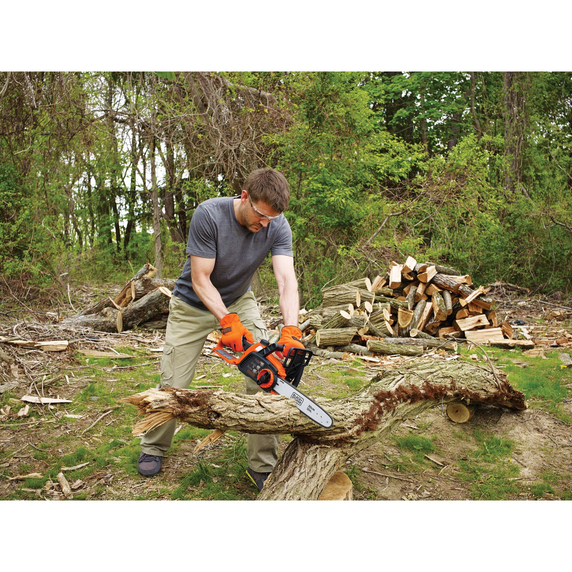 40 volt MAX lithium 12 inch chainsaw being used by a person to cut tree trunk.