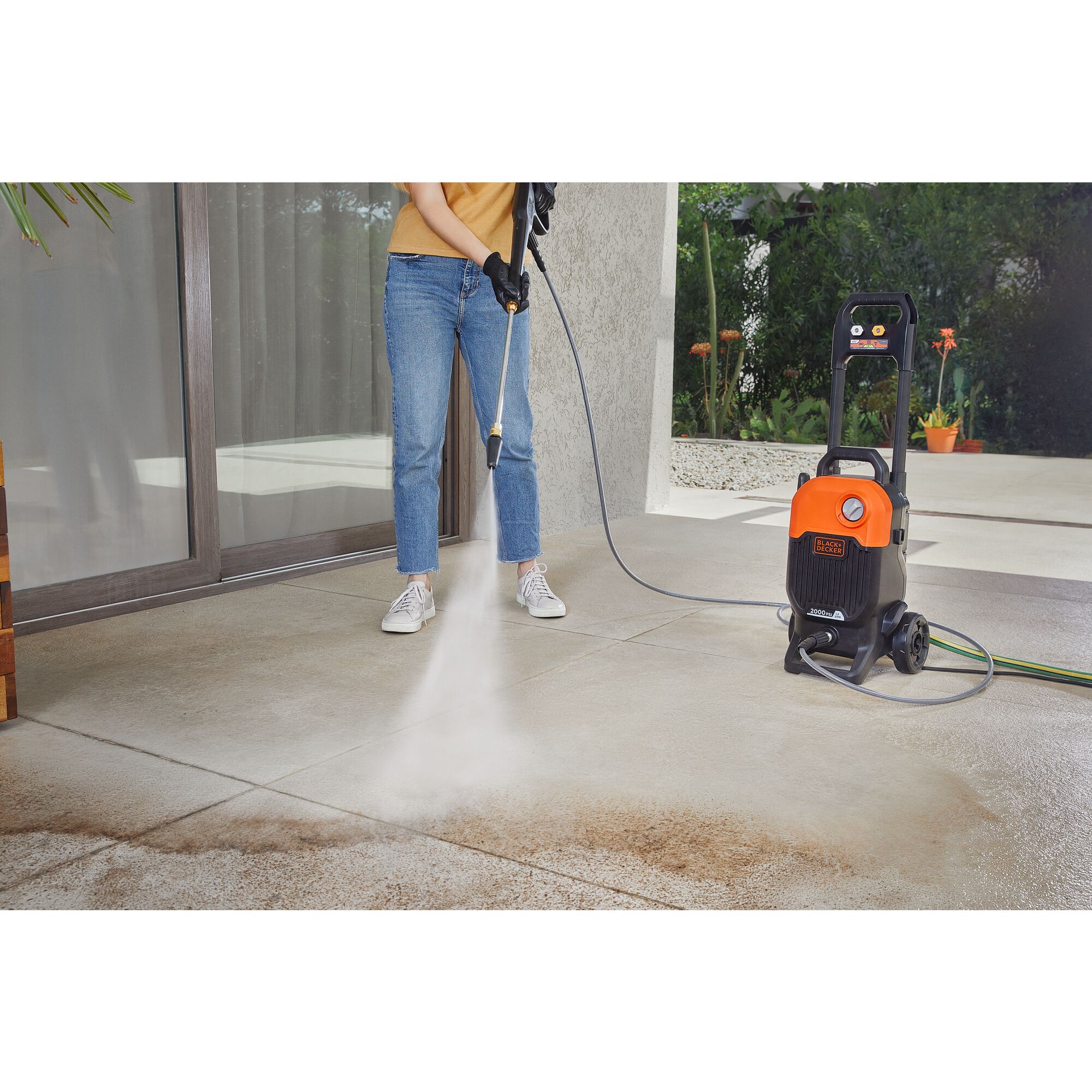 Person using BLACK+DECKER 2,000 MAX psi* pressure washer to clean tile floor