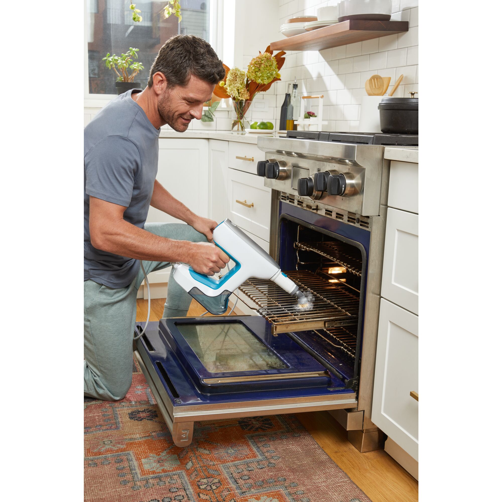 Man cleaning inside an open oven using steam mop accessory
