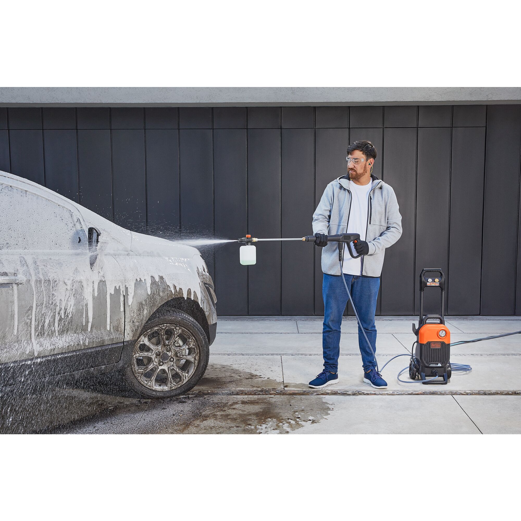 Person using BLACK+DECKER 2,000 MAX psi* pressure washer to clean a car