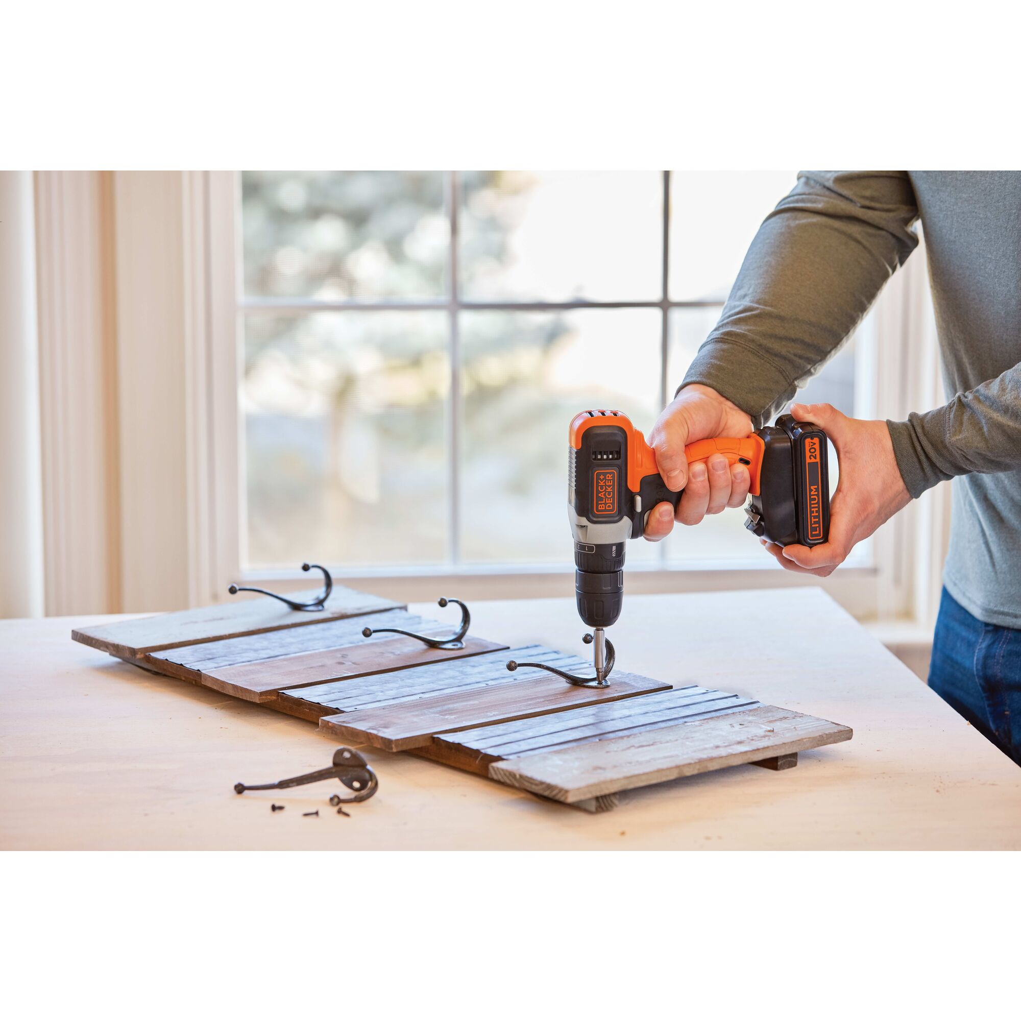 Person using handheld cordless drill on a table in a home