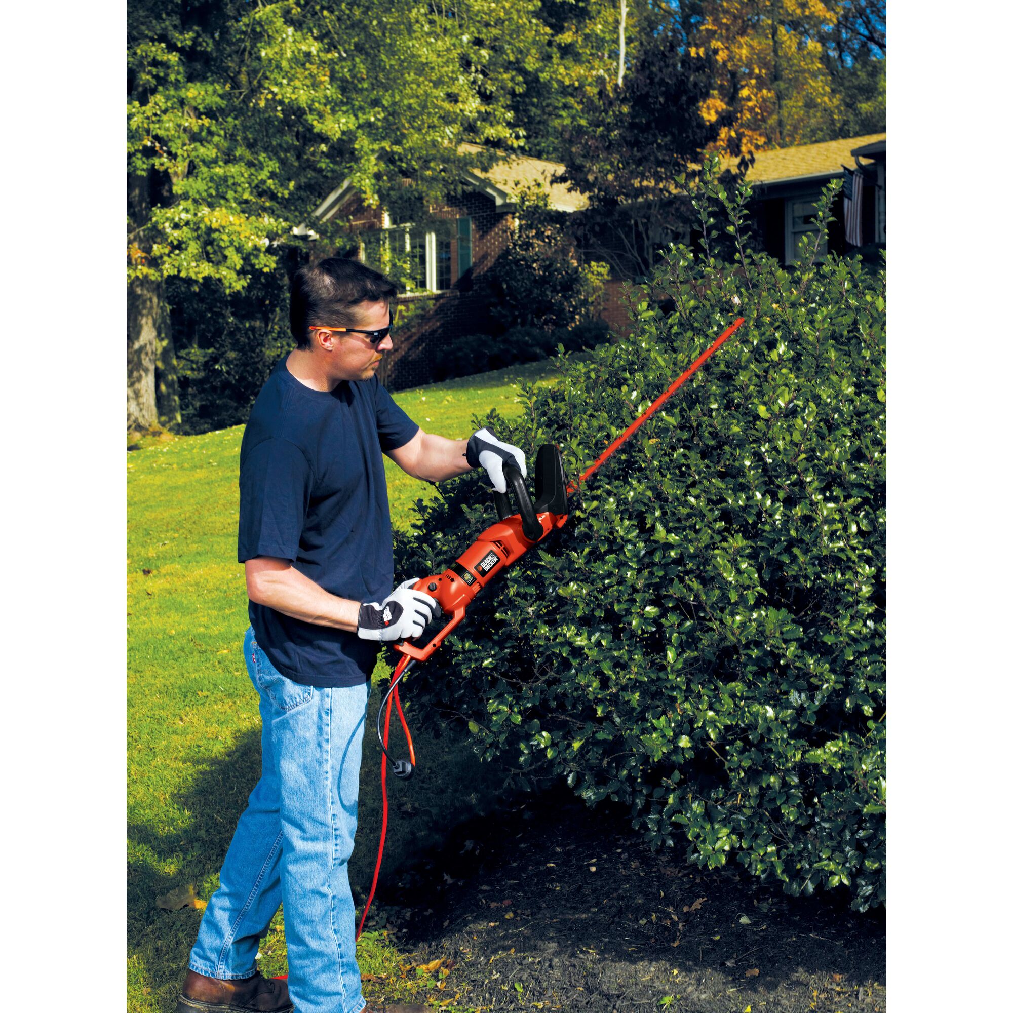 24 inch hedge trimmer with rotating handle being used to trim a bush.