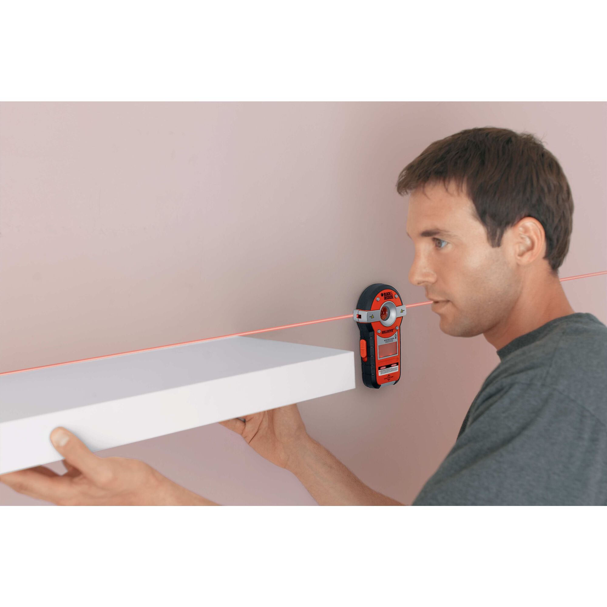 BullsEye auto leveling laser with stud sensor being used by a person to install a shelf.