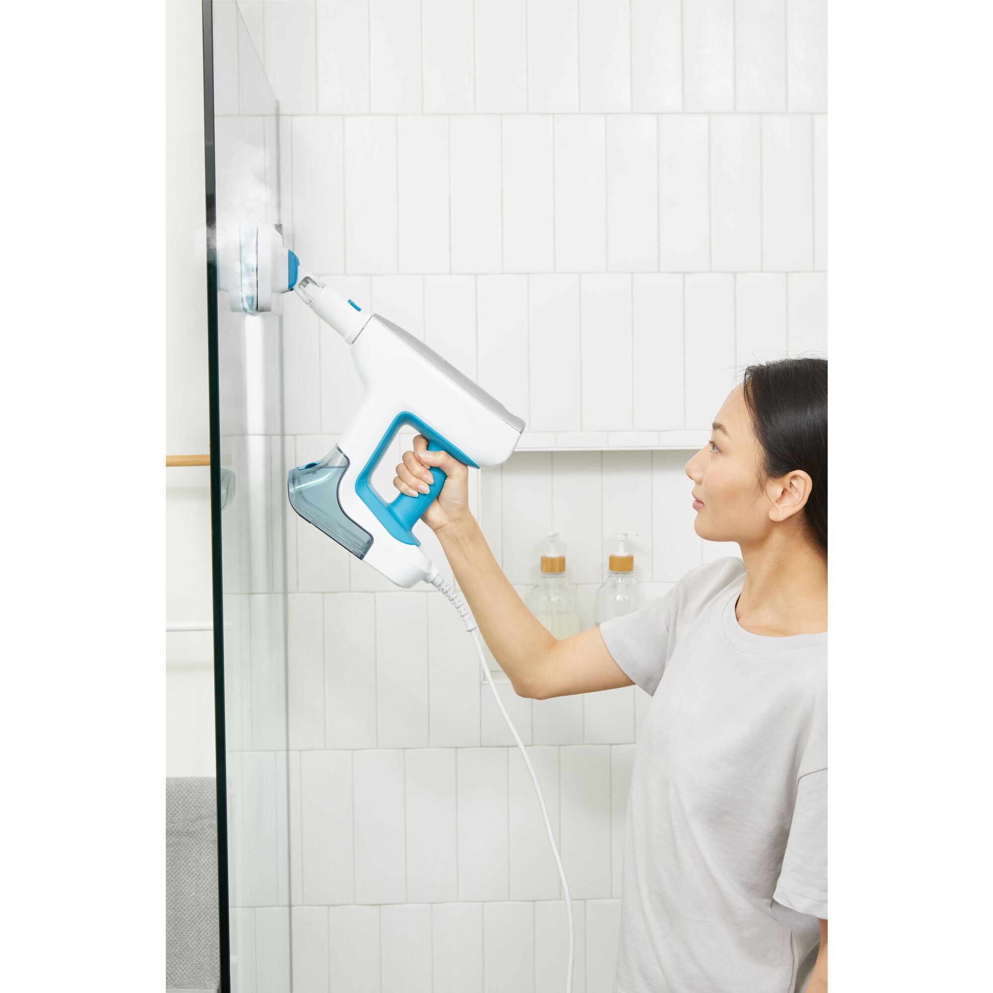 Woman cleaning shower door with steam mop accessory