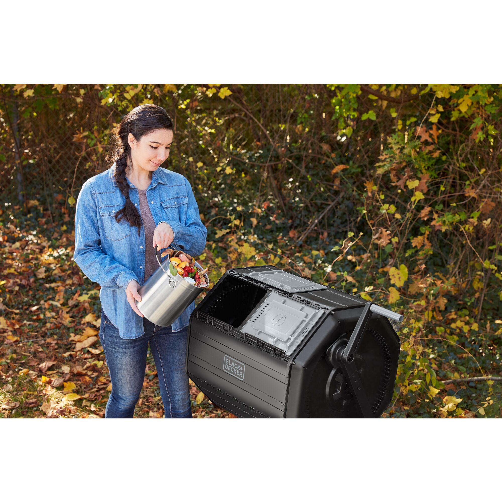 Woman dumping food scraps from the BLACK+DECKER Countertop Compost Bin into the BLACK+DECKER Tumbler Composter