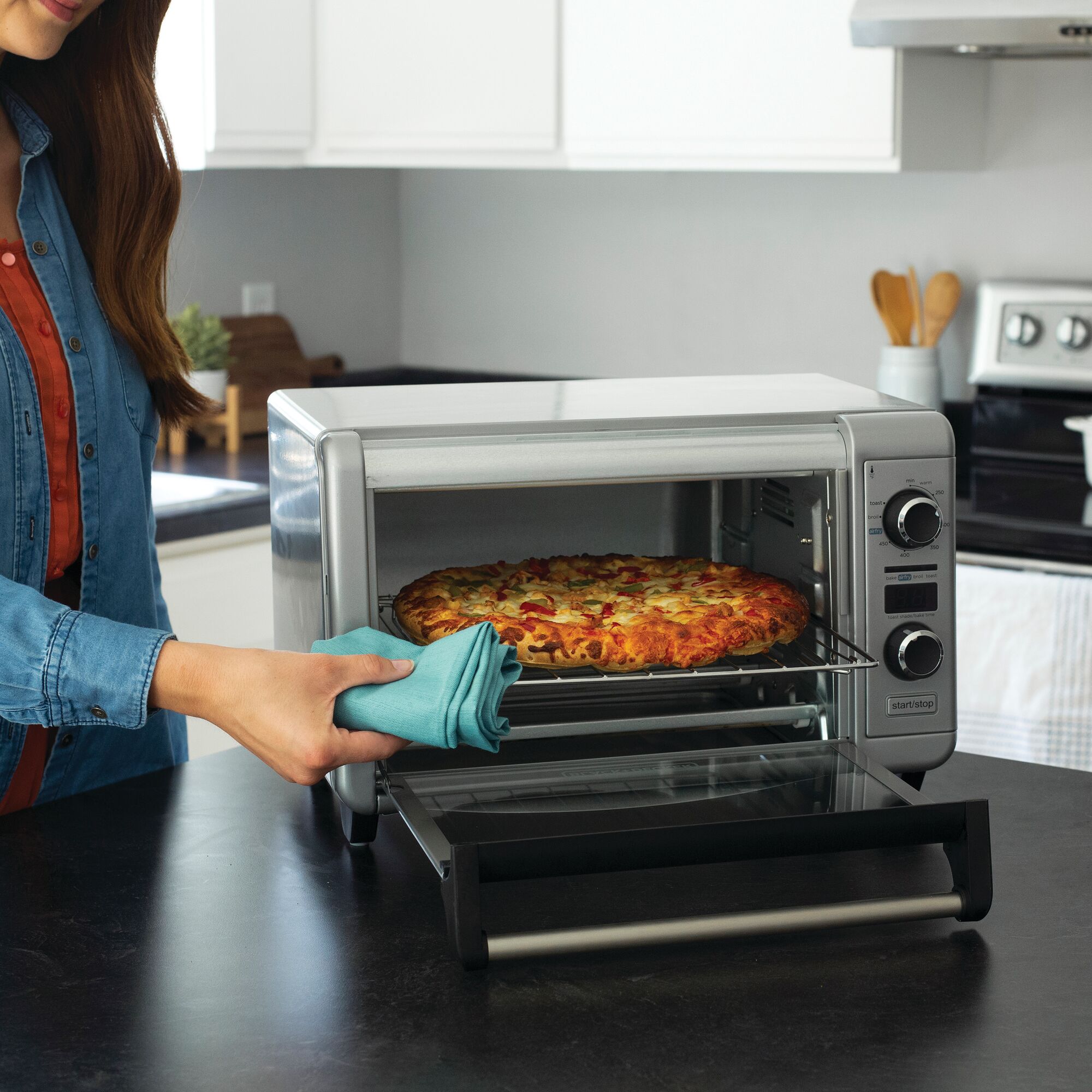 Crisp \u2018N Bake air fry digital convection countertop oven being used by a person to cook pizza.