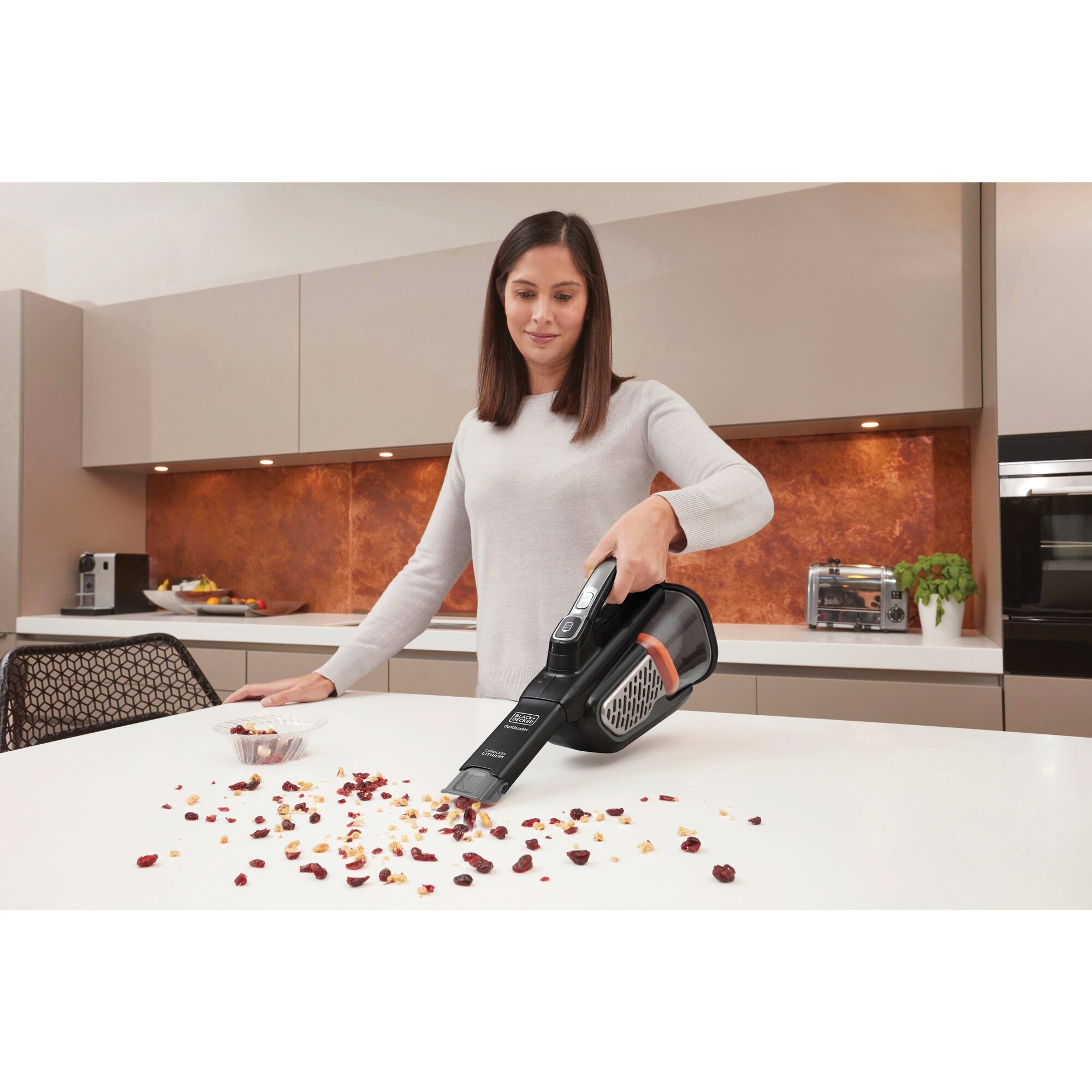 12 volt MAX dustbuster AdvancedClean cordless hand vacuum being used by a person to clean food spillage on kitchen counter.