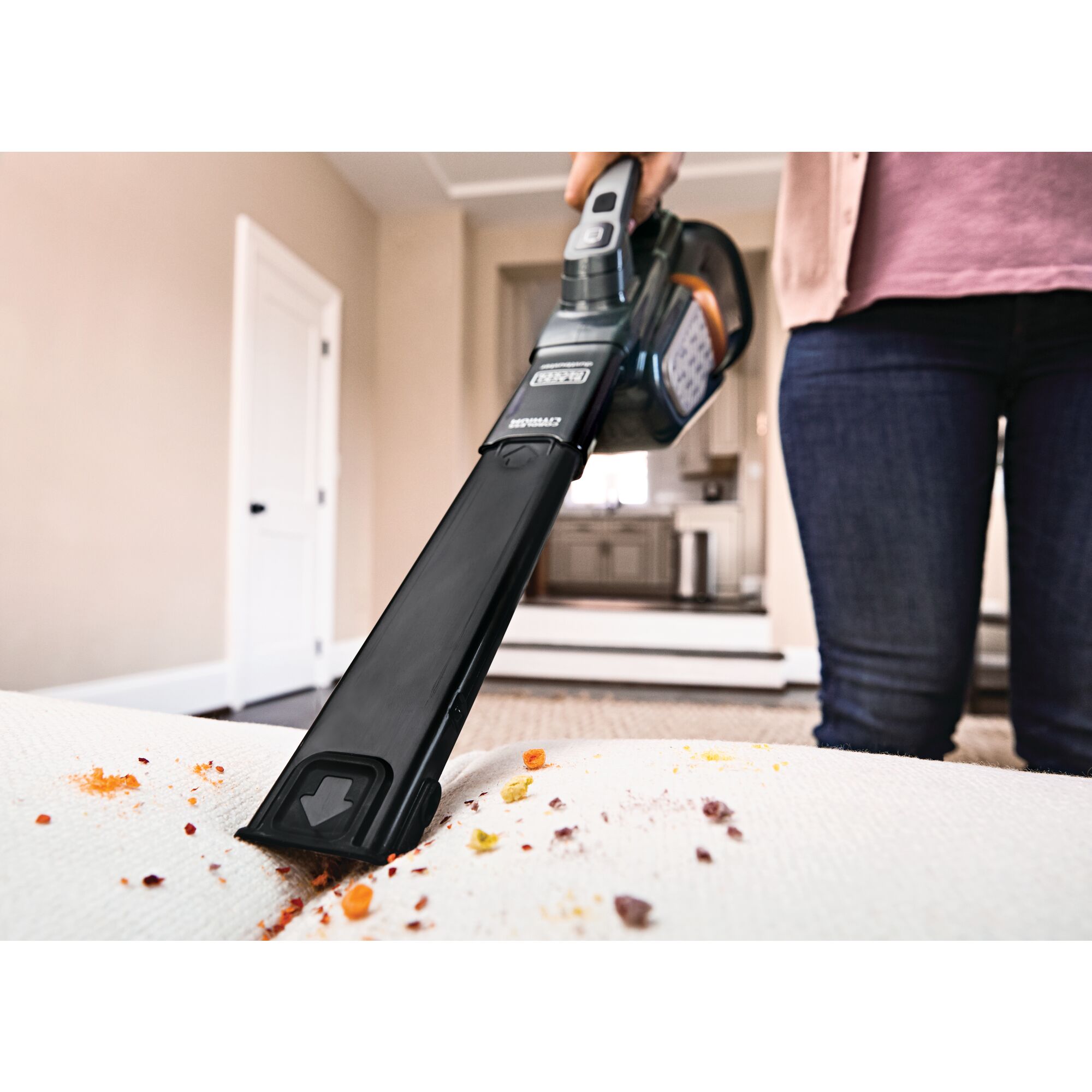 16 volt max dustbuster advanced clean plus hand vacuum being used to vacuum spilled material from a sofa.
