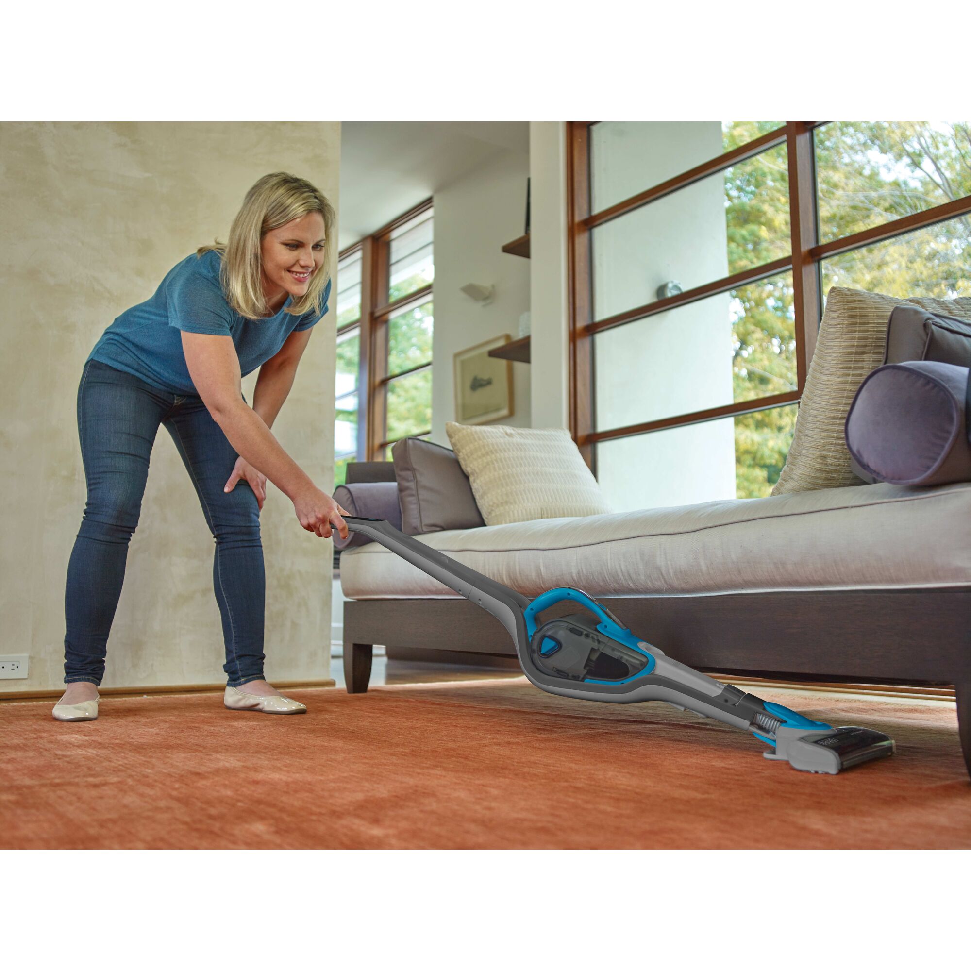 Cordless Lithium 2 in 1 Stick Vacuum being used for cleaning under sofa.