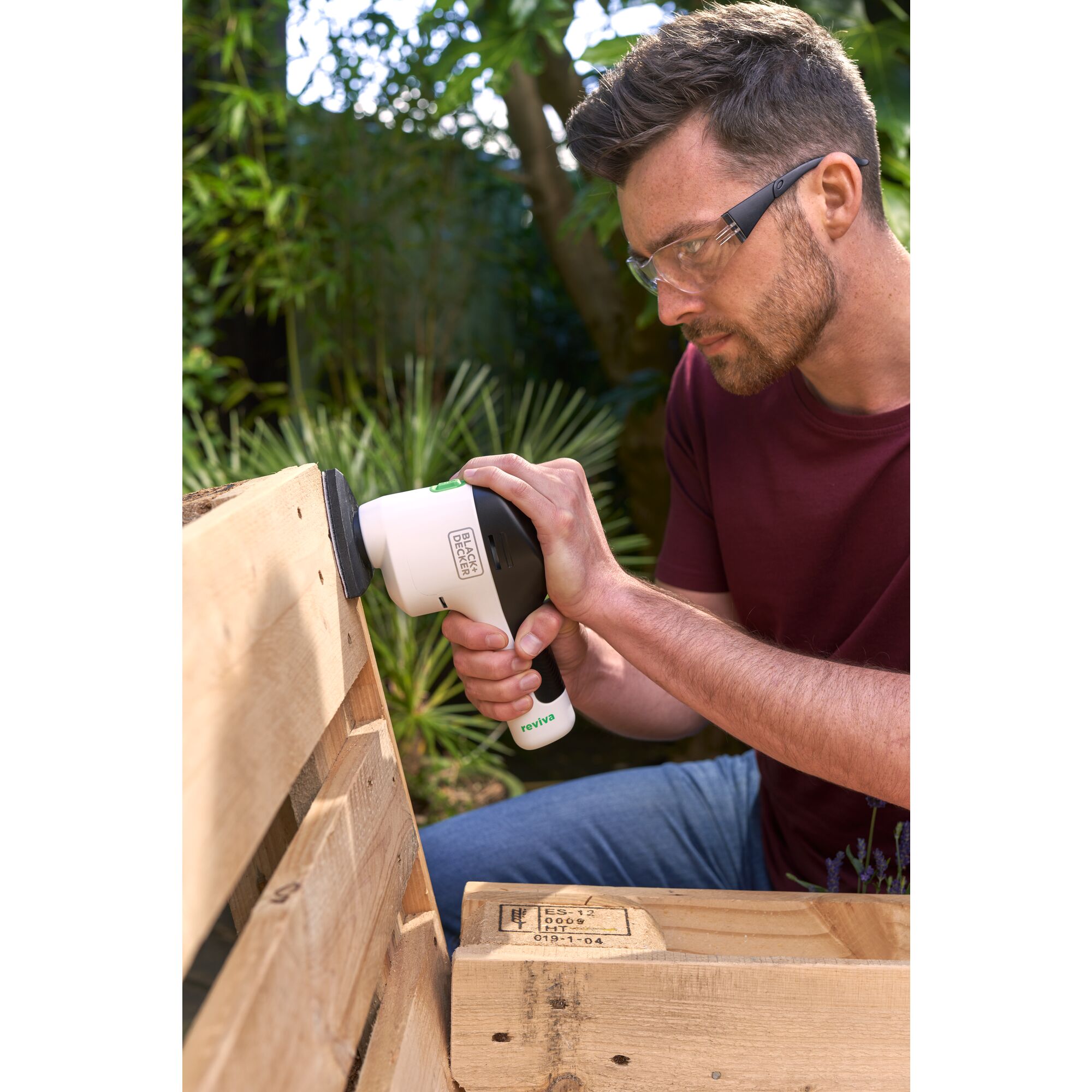 Man using reviva™ 12V MAX* Cordless Detail Sander to sand an outdoor bench.