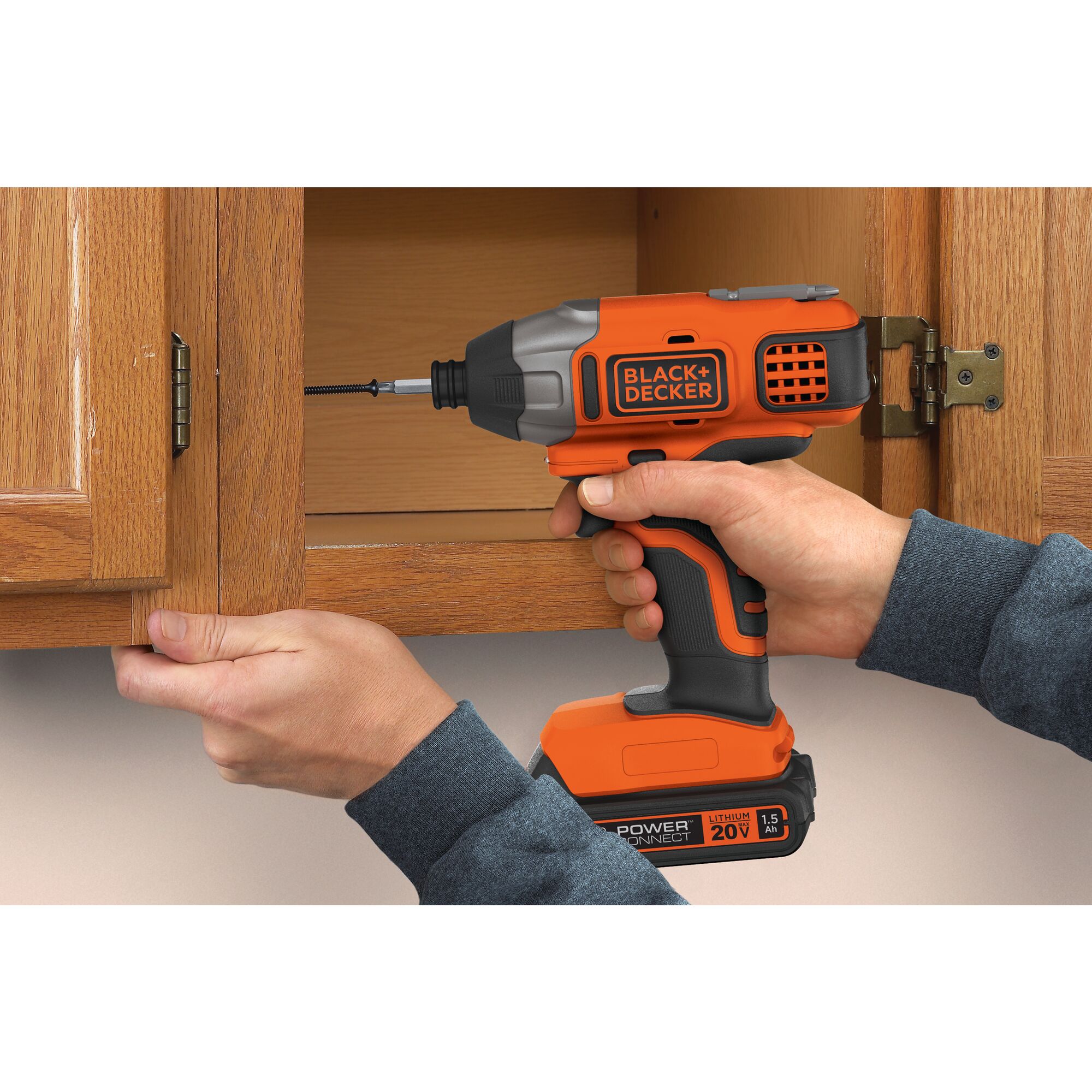 Lithium Impact Driver being used for screwing nail in wooden cabinet.