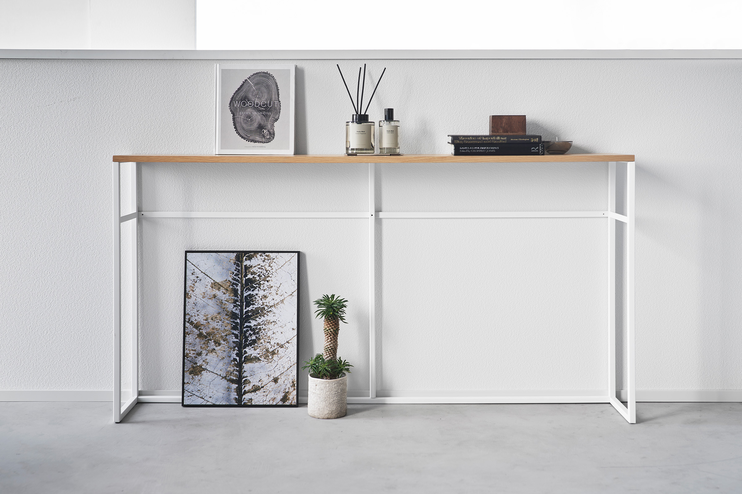 Straight view of the Long Console Table by Yamazaki Home in white with decorative items.