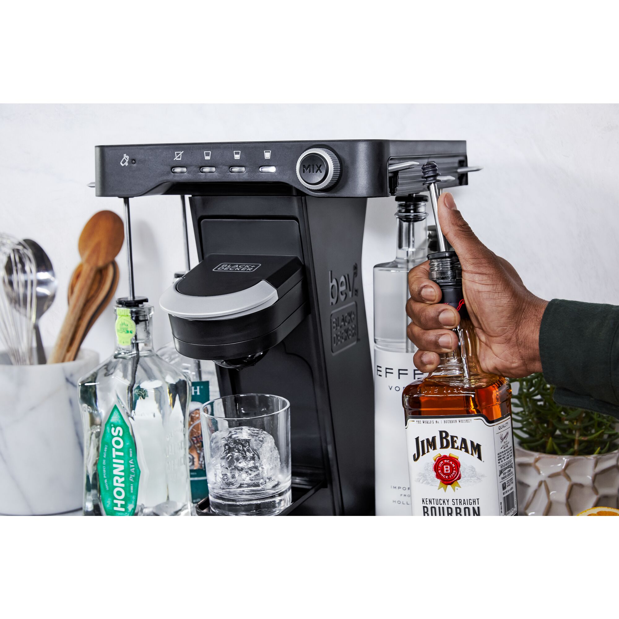 close-up, on the patio, of a man's hand loading a bottle of whiskey into the easy load liquor system on the bev by BLACK+DECKER\u2122 cocktail maker