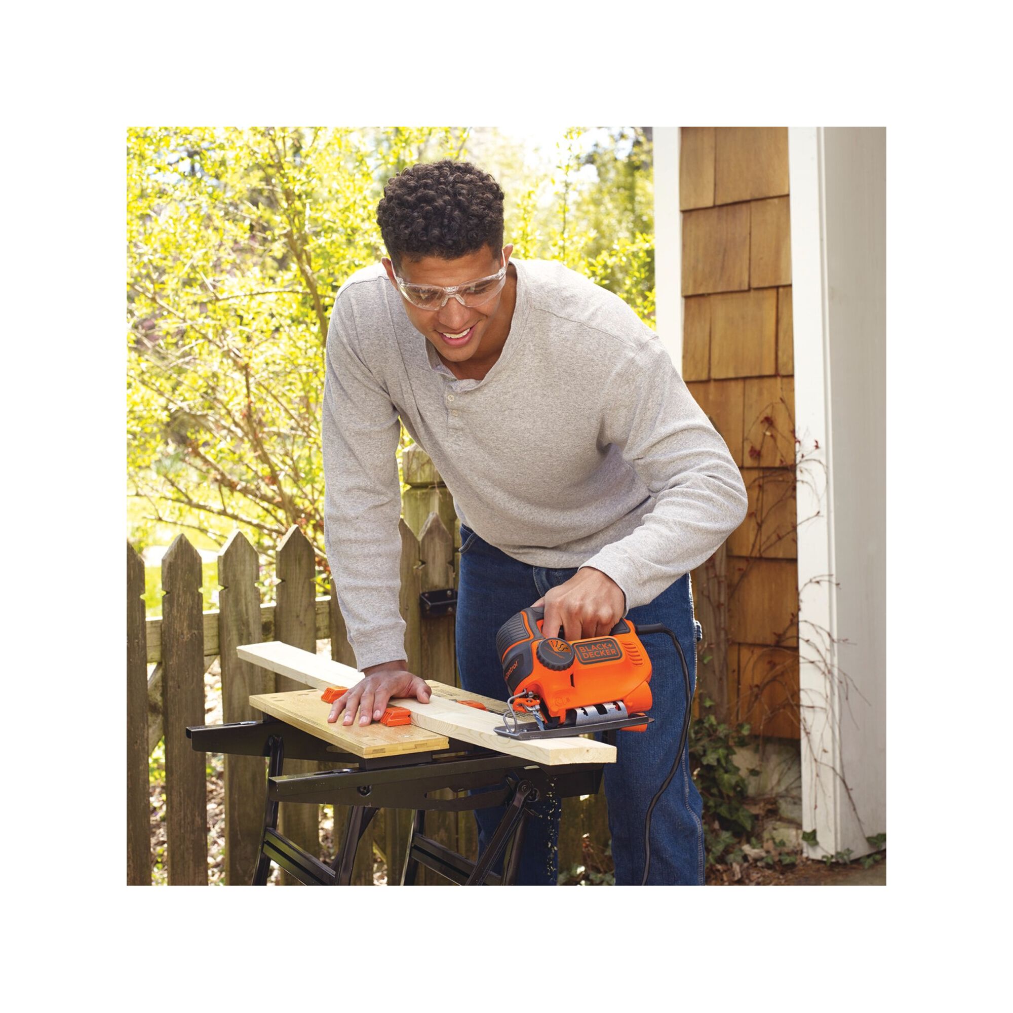 Man wearing safety goggles using BLACK+DECKER jig saw on a 1 x 4 piece of wood
