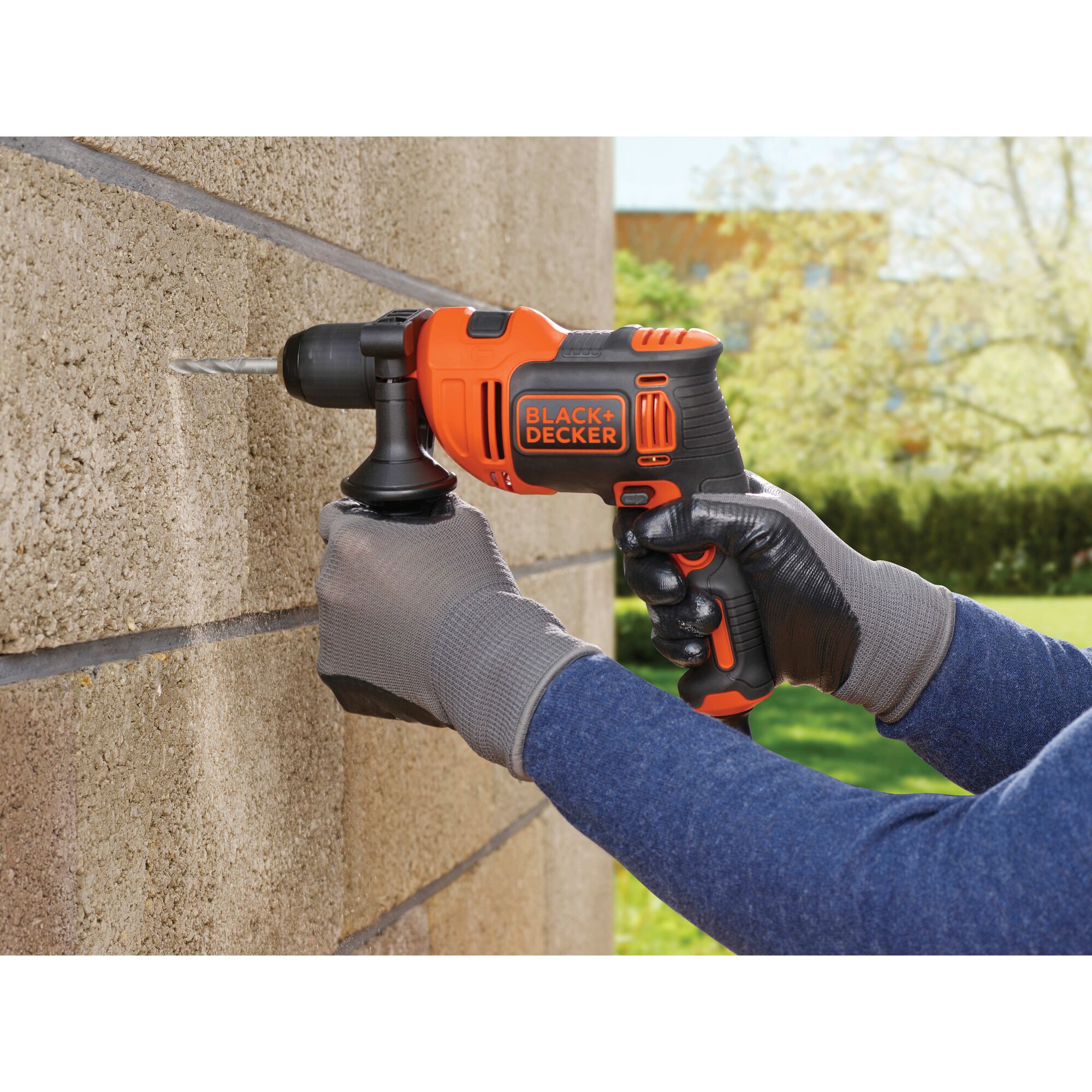 6.5 Ampere half inch hammer drill being used by a person to drill a hole in brick.