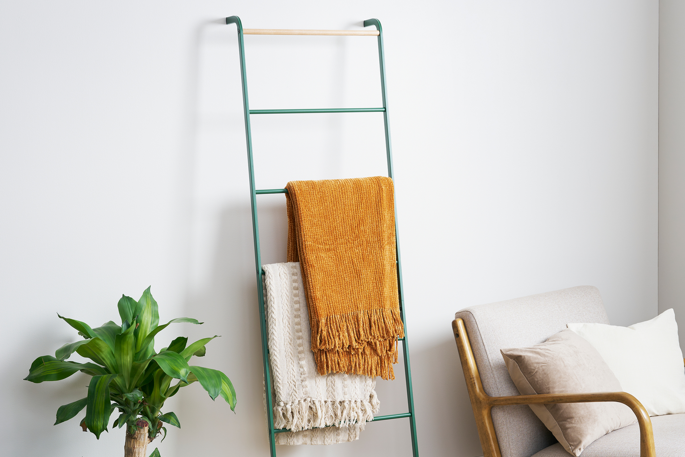 Forest Green Yamazaki Home Leaning Storage Ladder with two blankets stored.