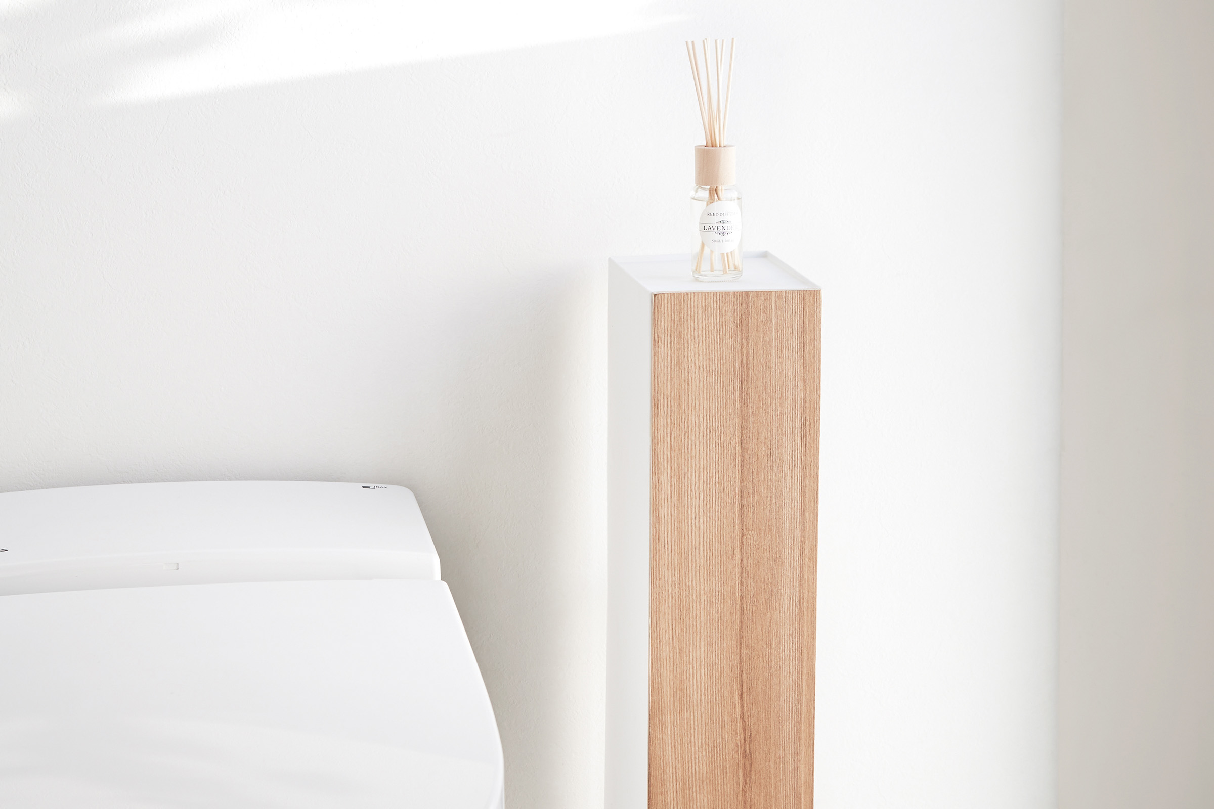 Front view of Toilet Paper Stocker displaying fragrance bottle in bathroom by Yamazaki Home.