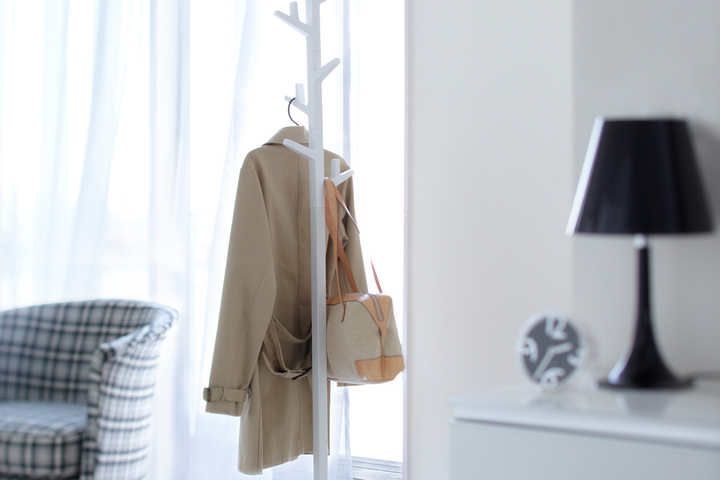 Front view of white Coat Rack holding jacket and purse by Yamazaki Home.