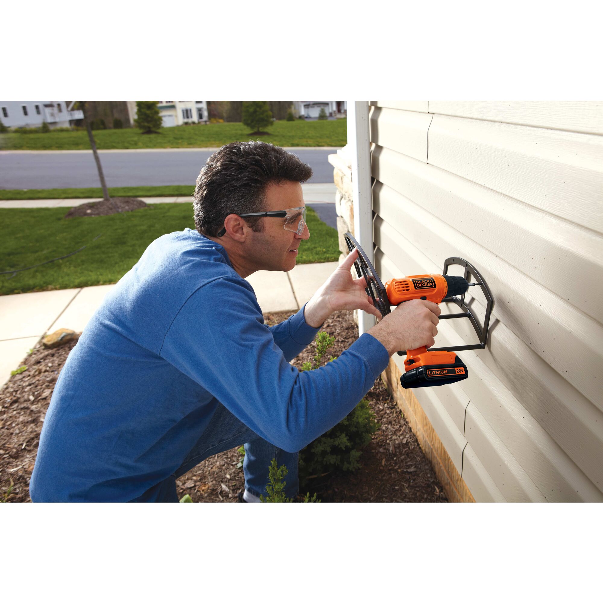 Lithium drill and driver with 30 accessories being used by a person to drill into the exterior of a house.