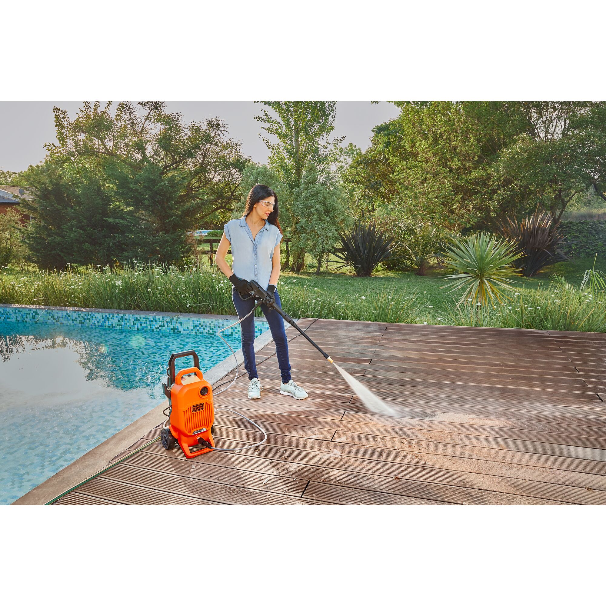 Woman cleaning a swimming pool deck with the BLACK+DECKER 1,850 MAX psi* pressure washer with 15\u02da nozzle