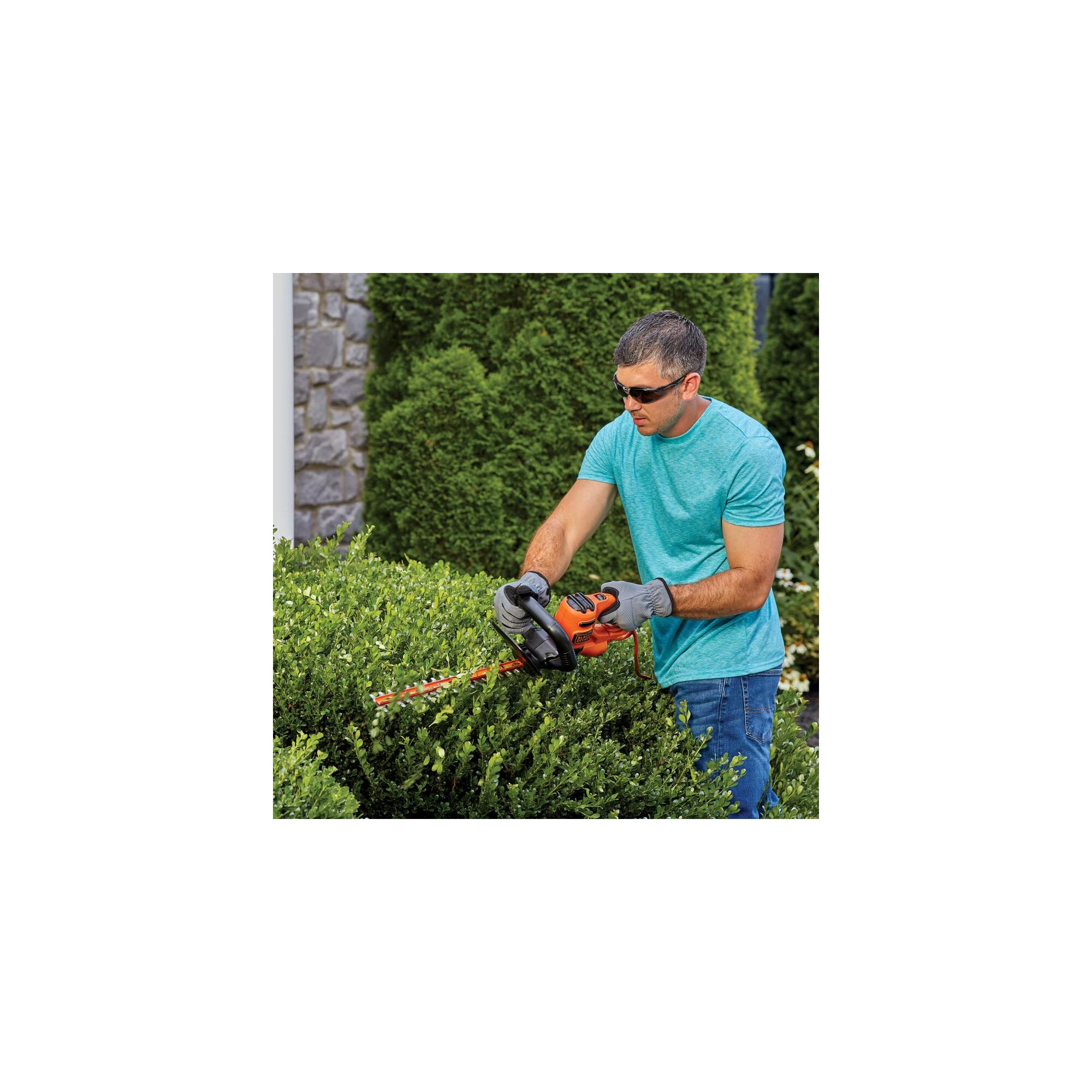 20 inch saw blade electric hedge trimmer being used by a person.