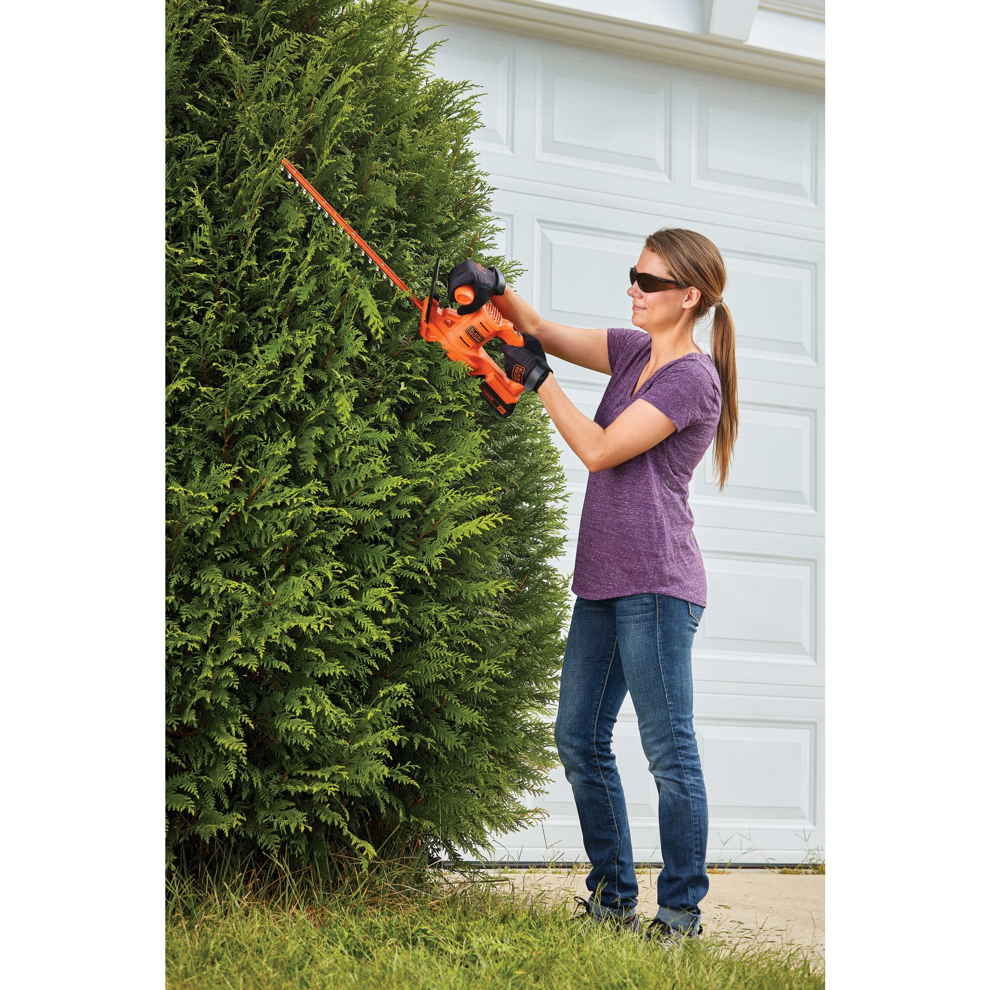 Cordless hedge trimmer being used by a person to trim bushes.\r\n
